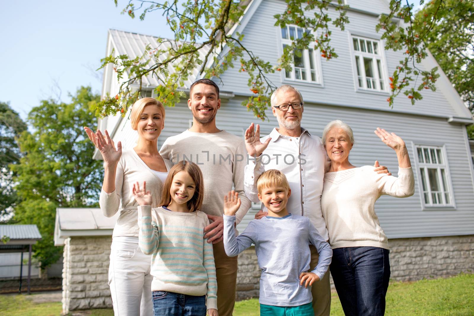 family, generation, gesture, home and people concept - happy family standing in front of house waving hands outdoors