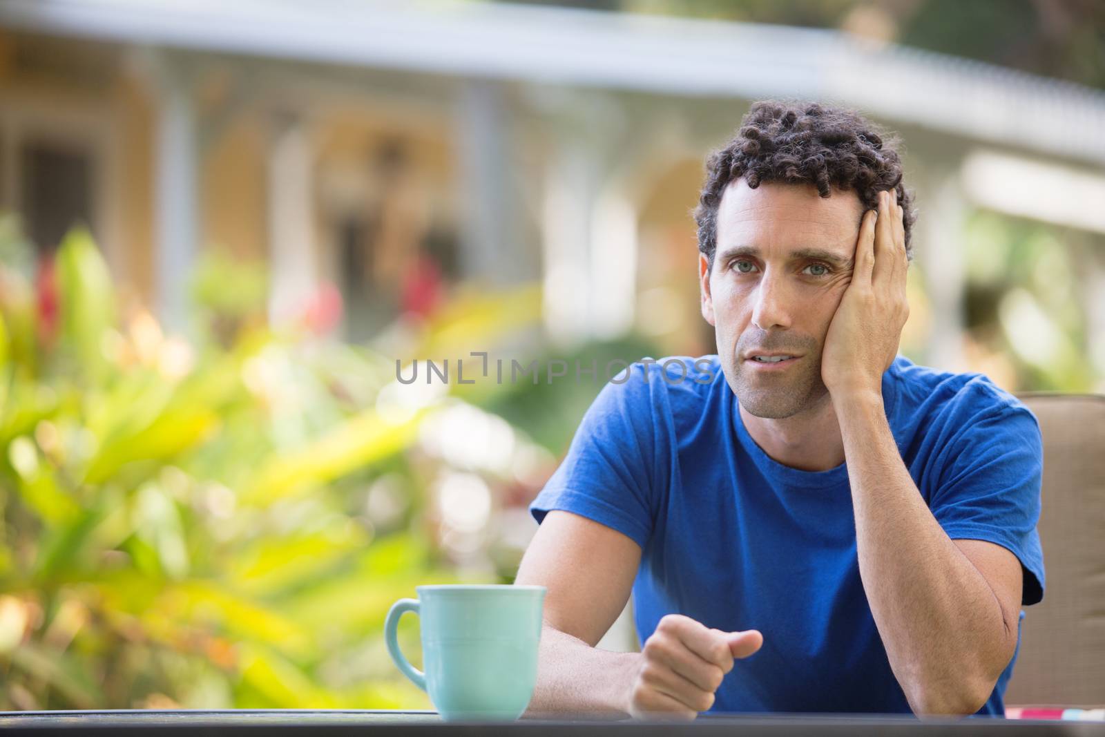 Tired man with hand on head sitting outdoors