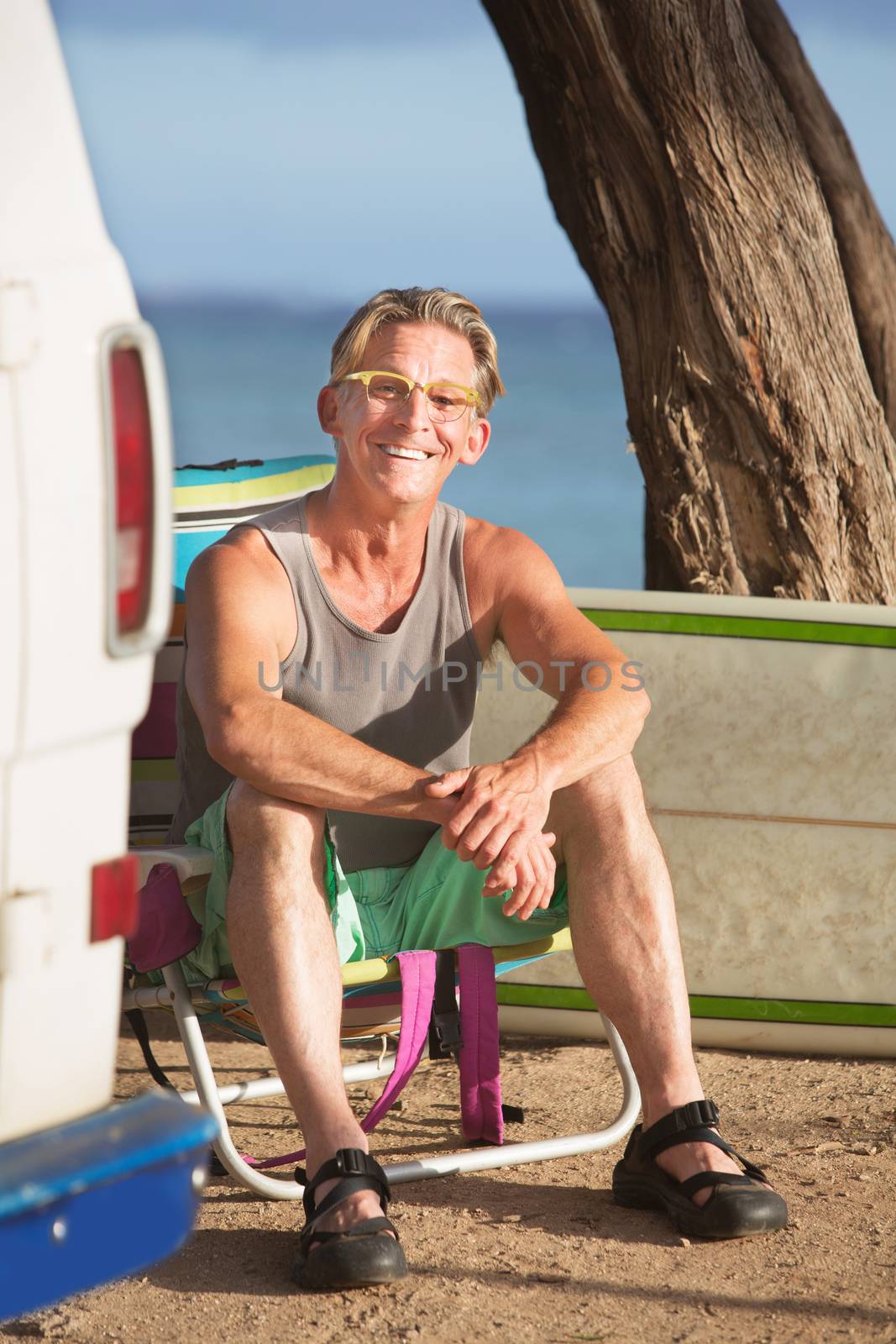 Smiling adult Caucasian surfer sitting outdoors
