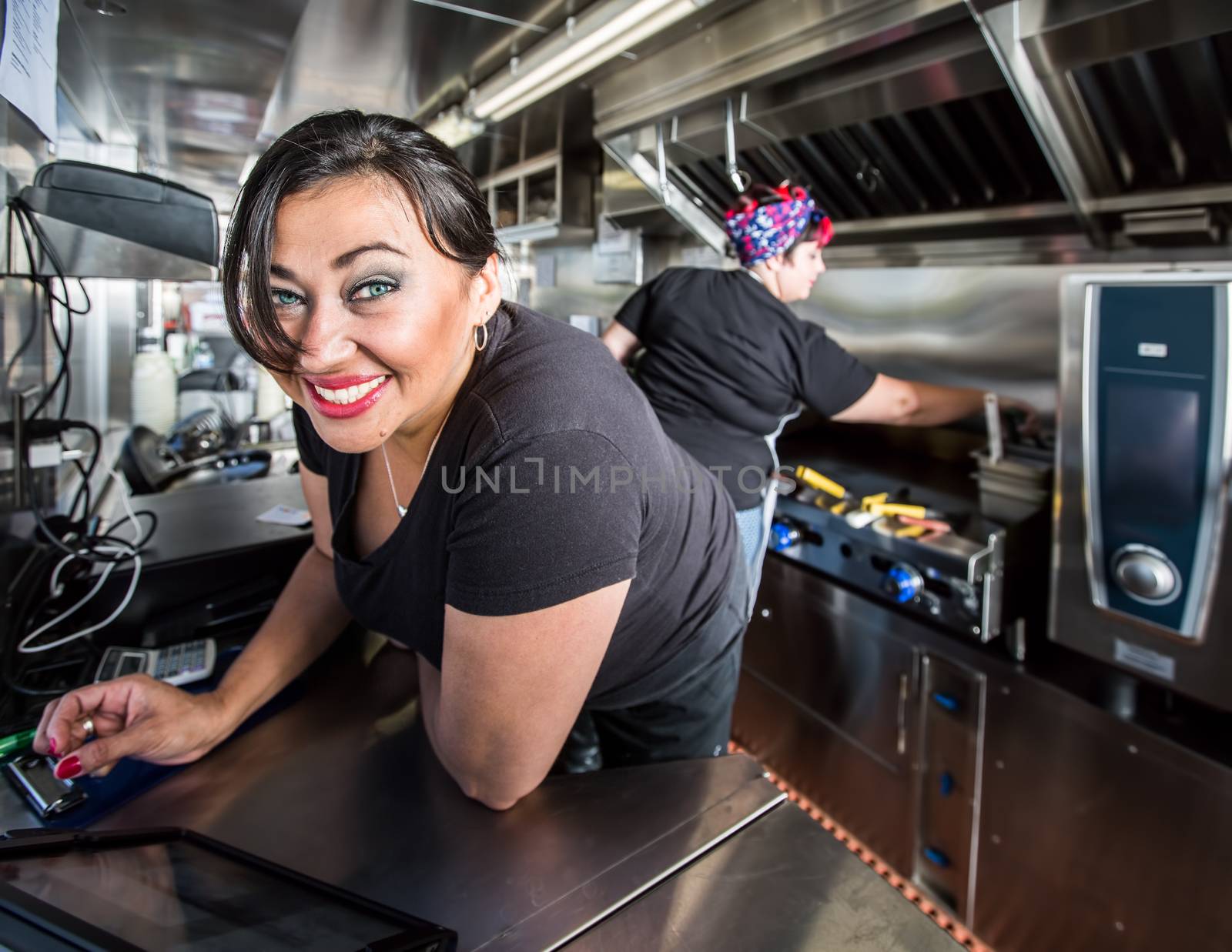 Dark haired smiling cashier with blue eyes on food truck