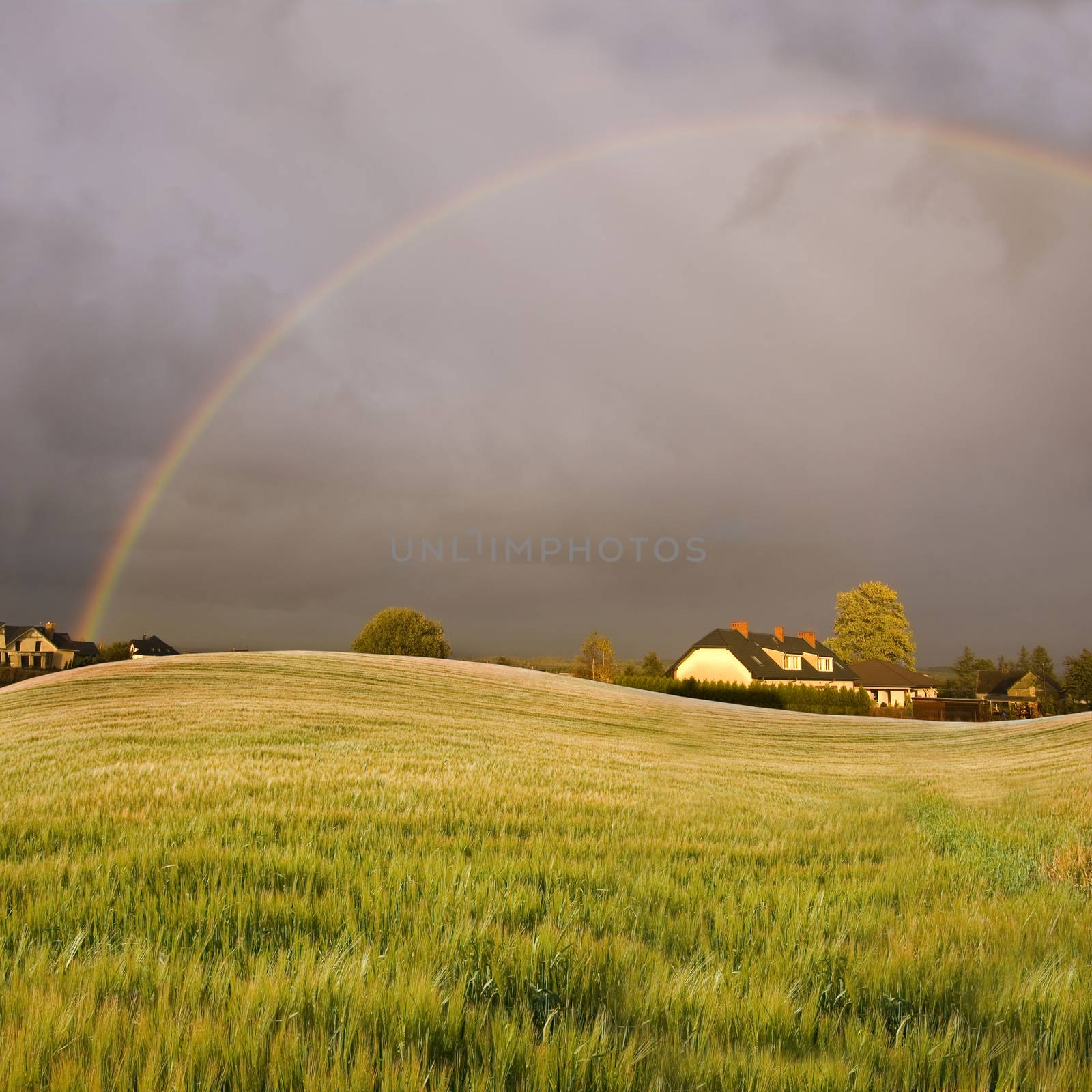 Weather conceptual image. Rainbow over the small village.