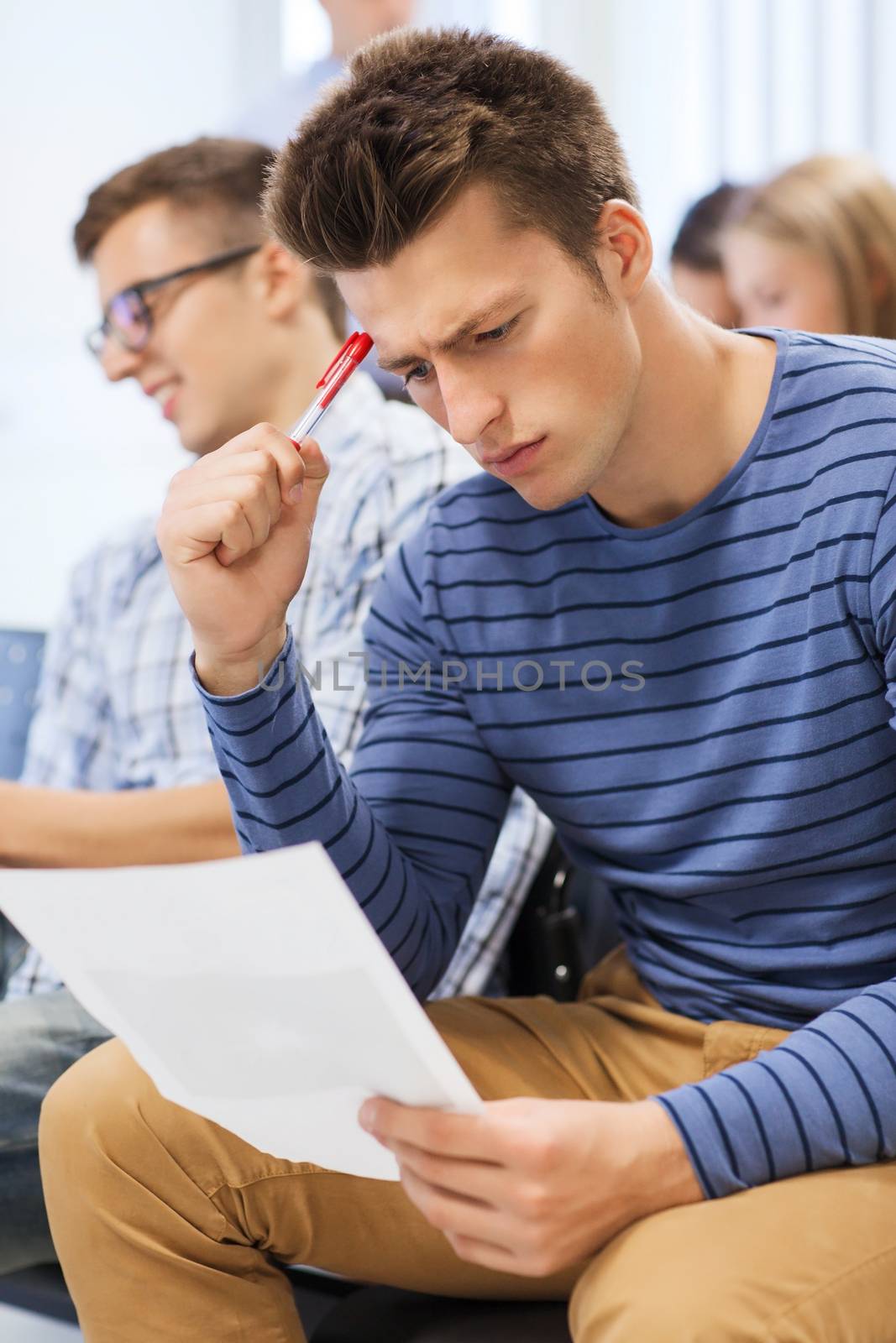 education, high school, teamwork and people concept - student with paper and pen sitting with group of classmates