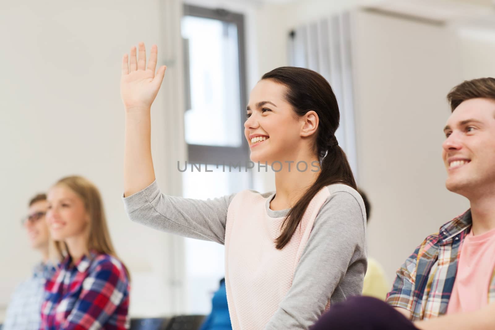 education, high school, teamwork and people concept - group of smiling students raising hand in lecture hall