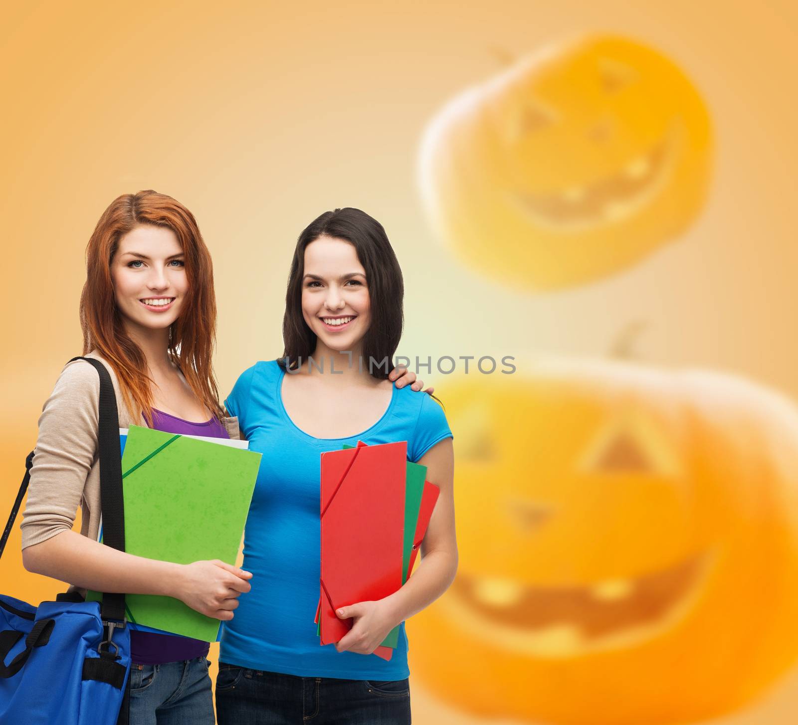 education, holidays, school, friendship and people concept - smiling student girls with books and bag over halloween pumpkins background