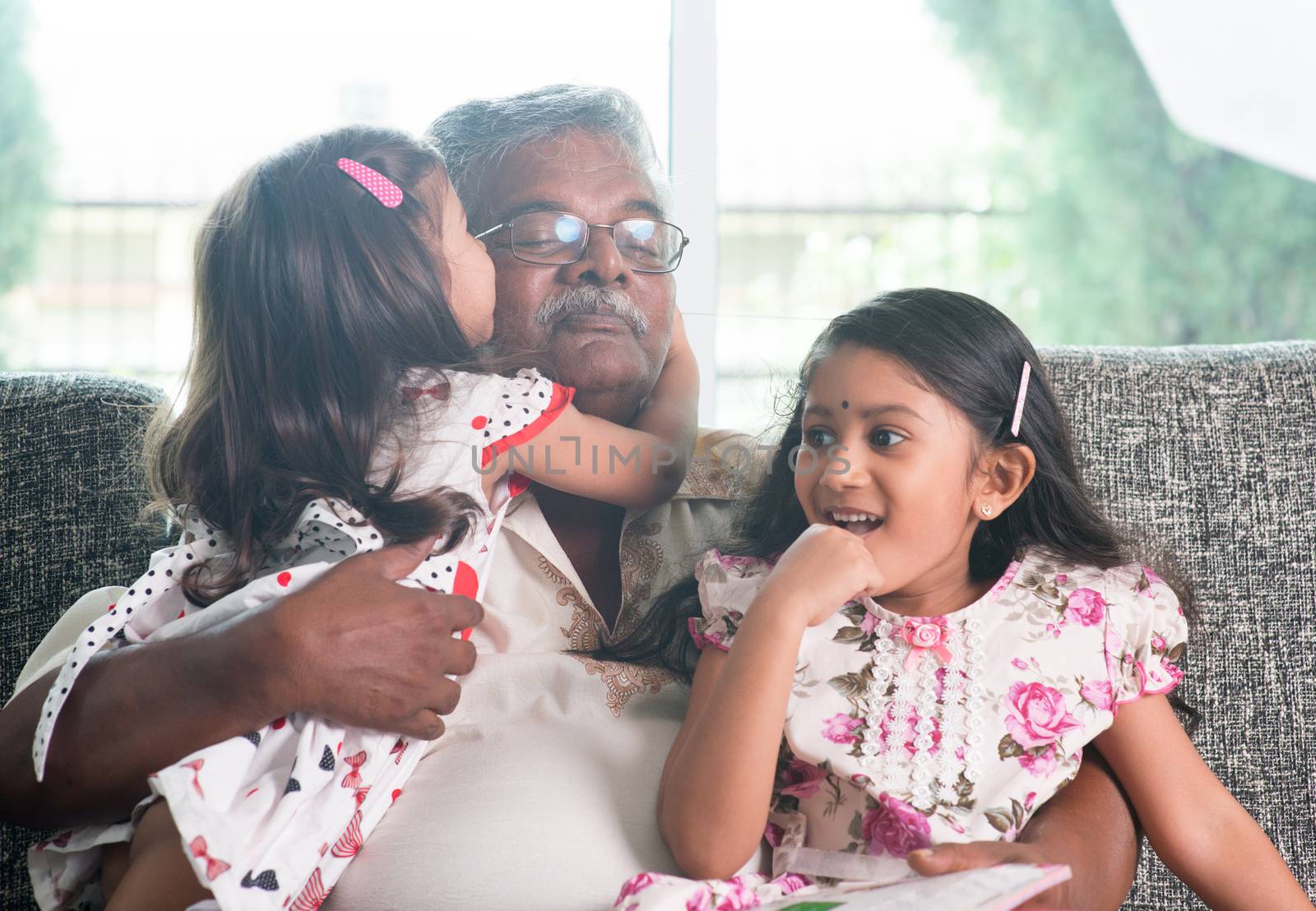 Portrait of happy Indian family at home. Grandchild kissing grandparent. Grandfather and granddaughters. Asian people living lifestyle.