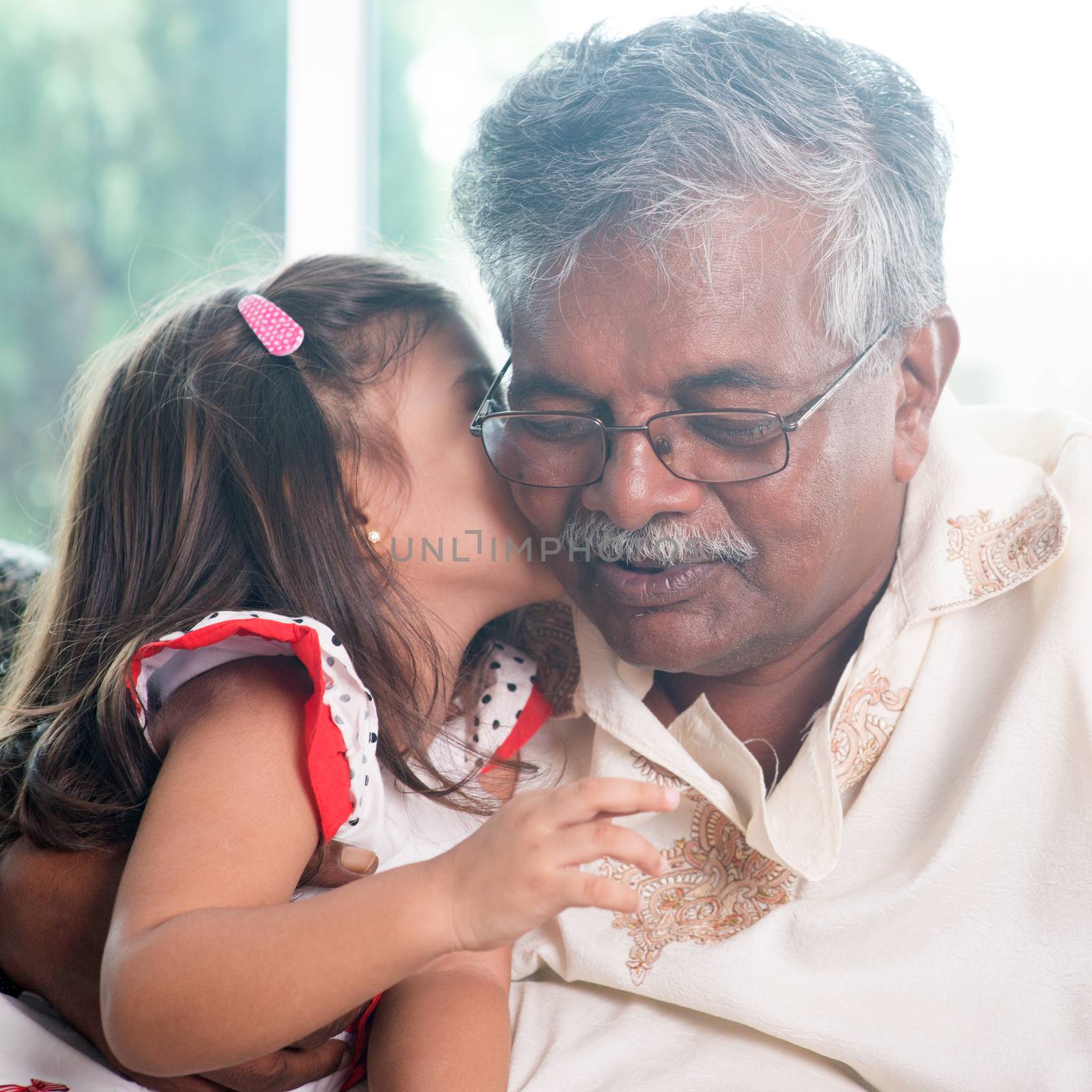 Portrait of Indian family at home. Grandchild kissing grandparent. Grandfather and granddaughter. Asian people living lifestyle.