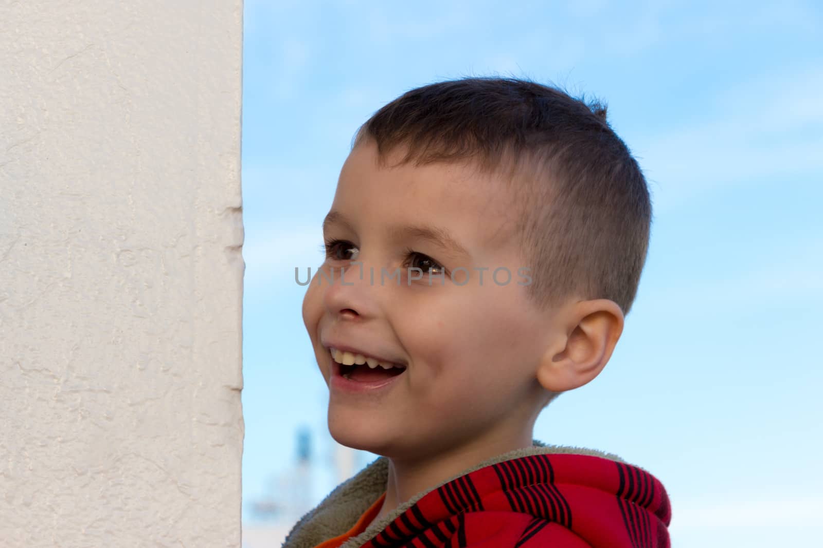 A little boy laughing next to a white wall. Captured at Port Melbourne