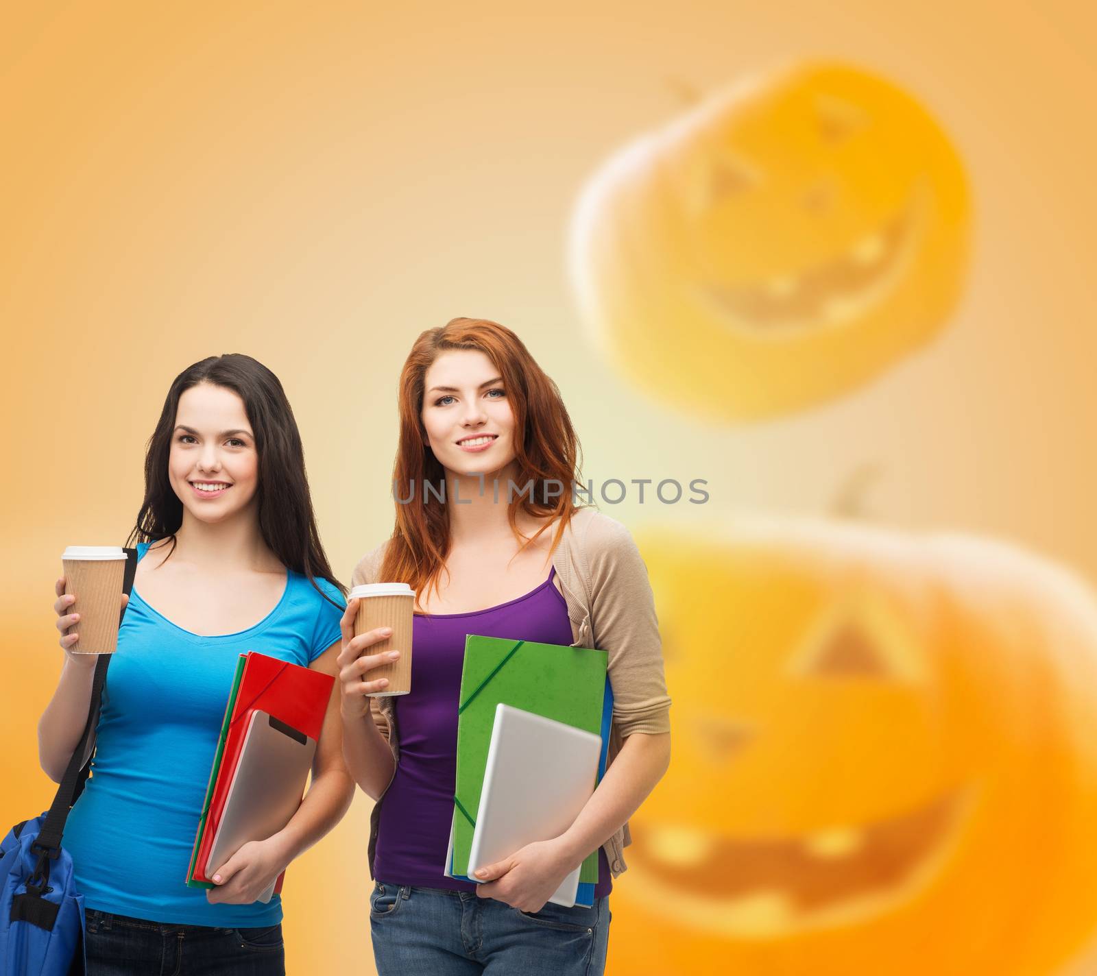 education, holidays, friendship, drinks and people concept - smiling student girls with books and paper coffe cups over halloween pumpkins background