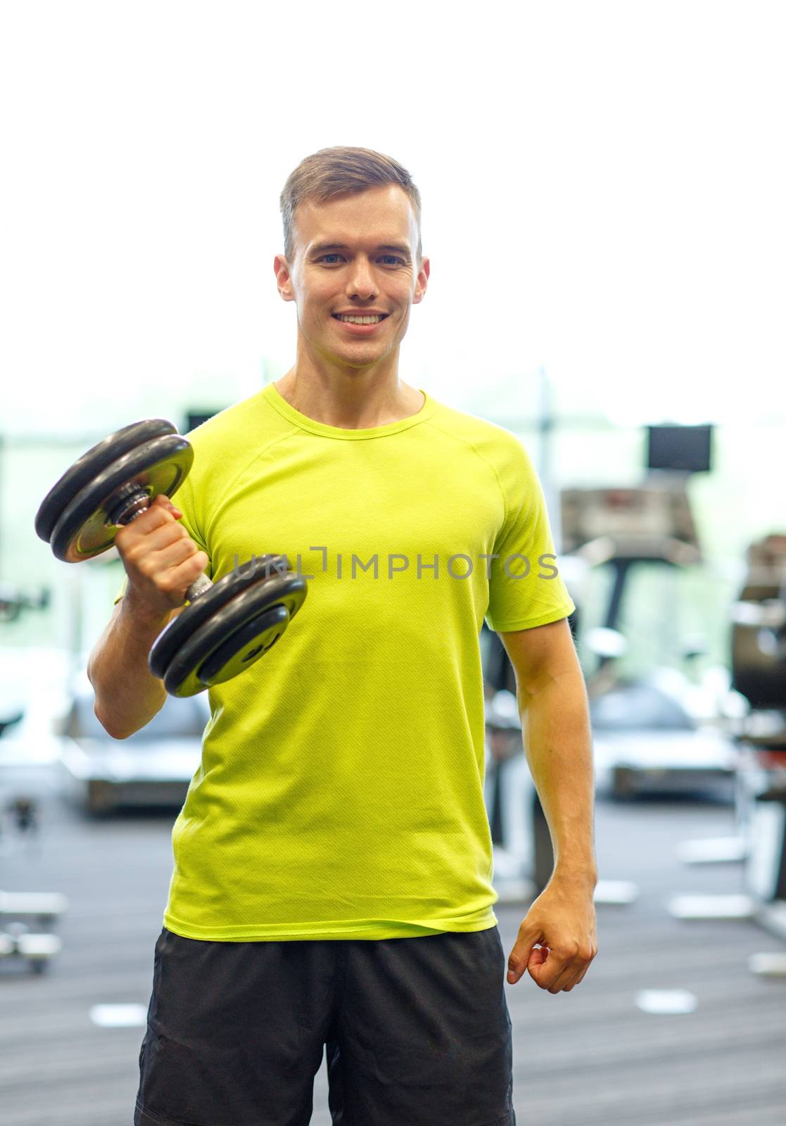 smiling man with dumbbell in gym by dolgachov