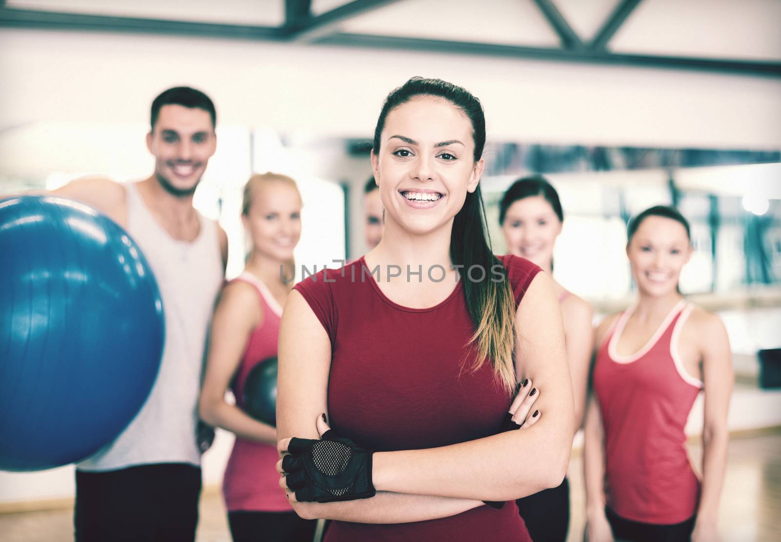 fitness, sport, training, gym and lifestyle concept - smiling woman standing in front of the group of people in gym