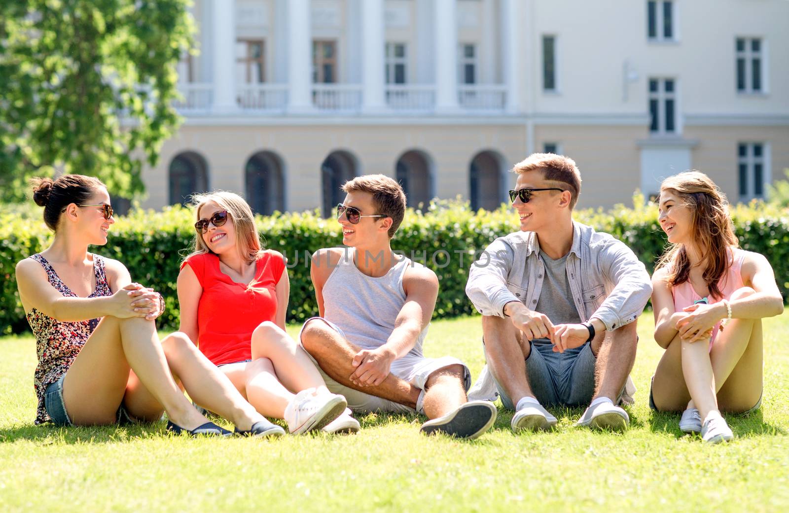 group of smiling friends outdoors sitting on grass by dolgachov