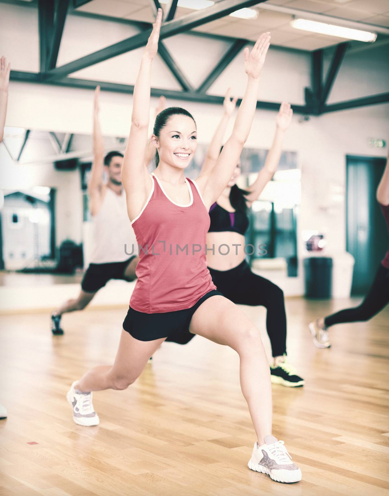 group of smiling people exercising in the gym by dolgachov