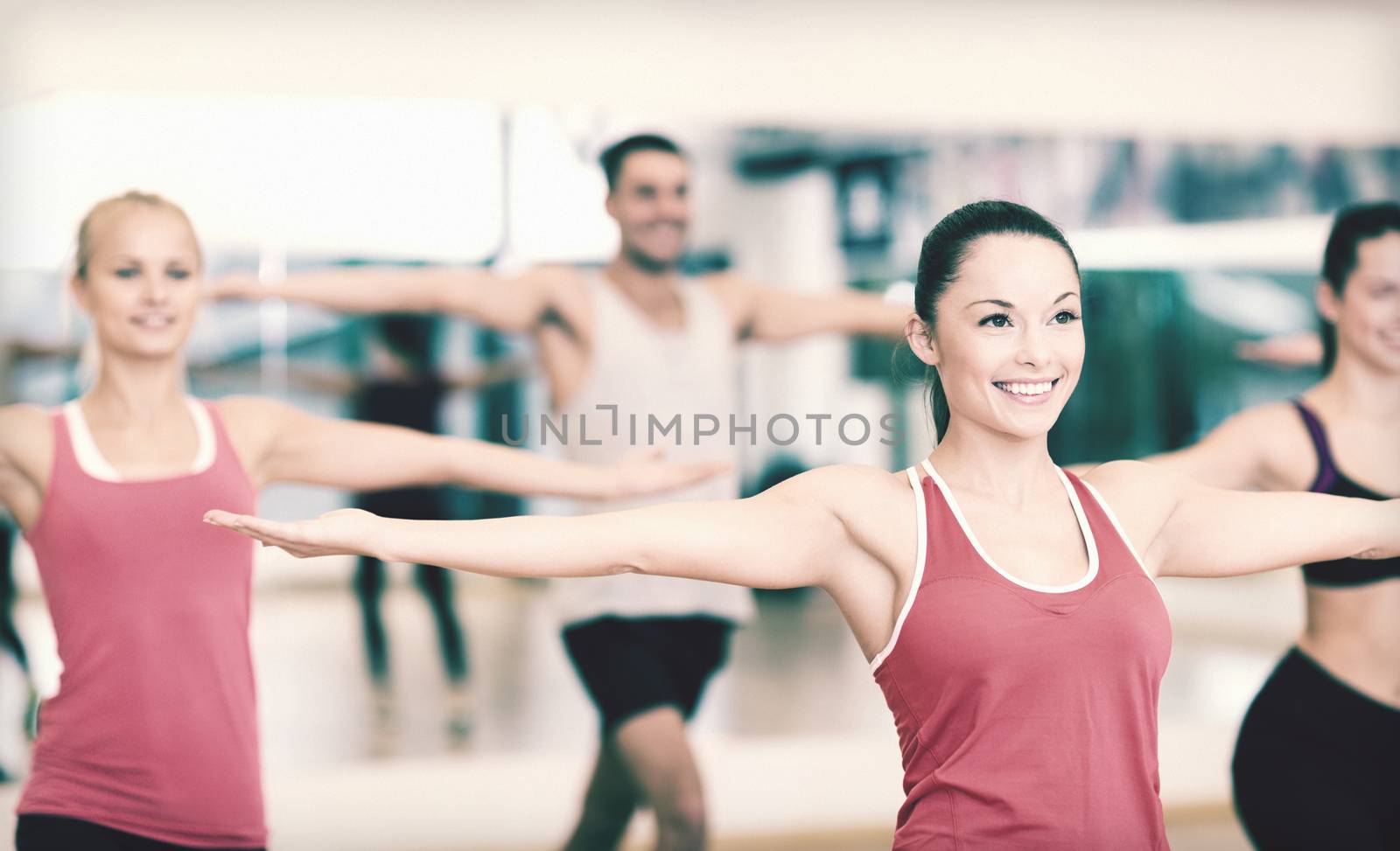 group of smiling people exercising in the gym by dolgachov