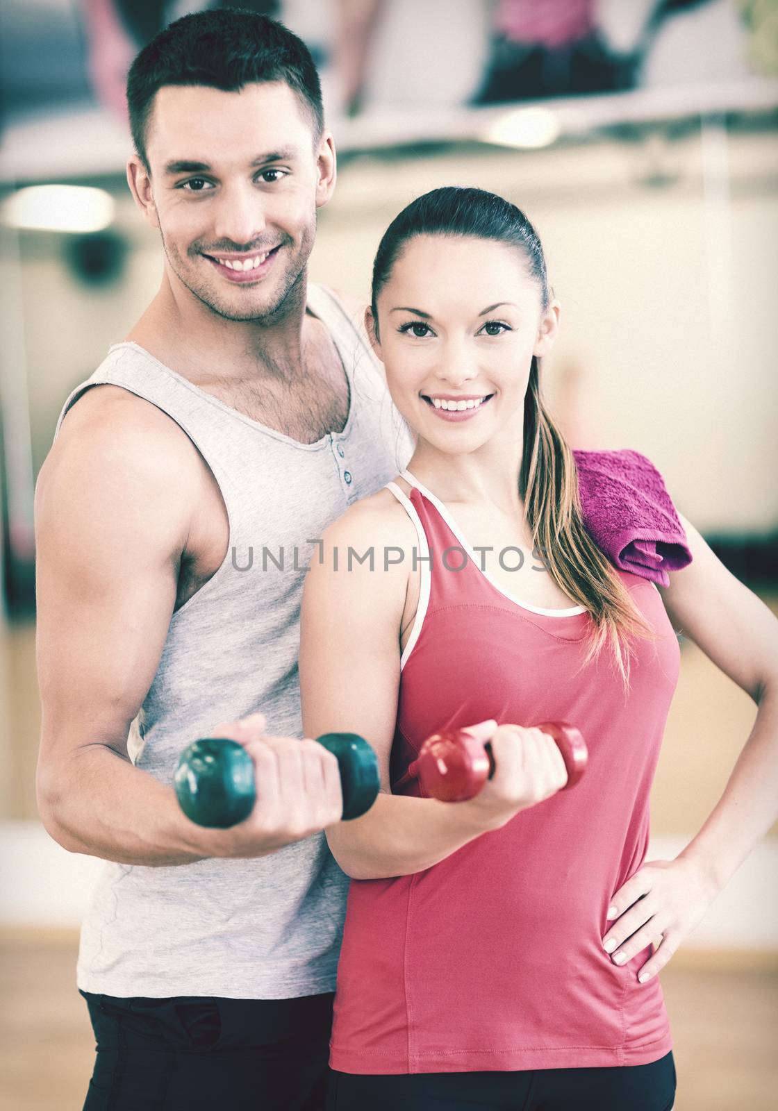 two smiling people working out with dumbbells by dolgachov