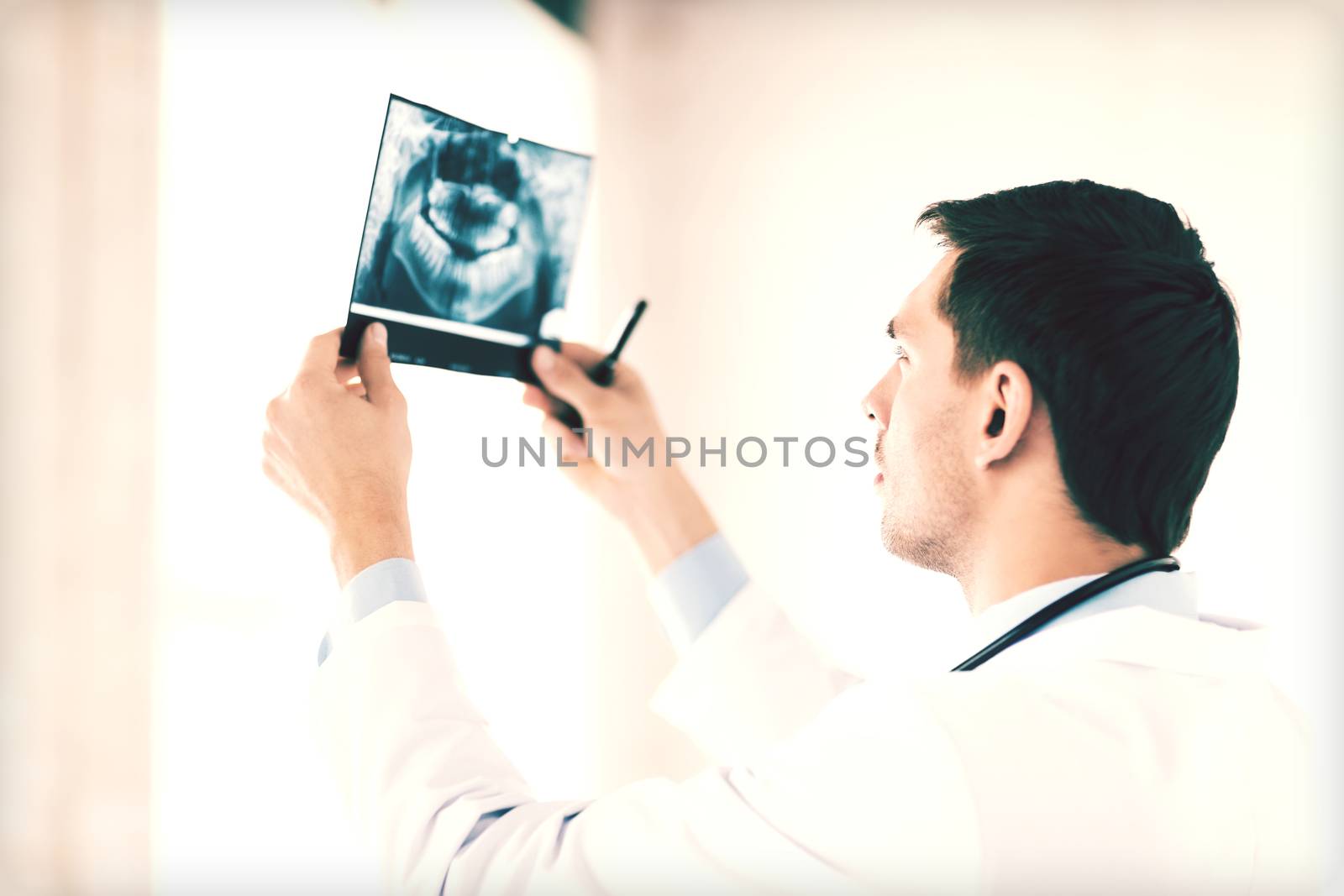 male doctor or dentist looking at x-ray by dolgachov