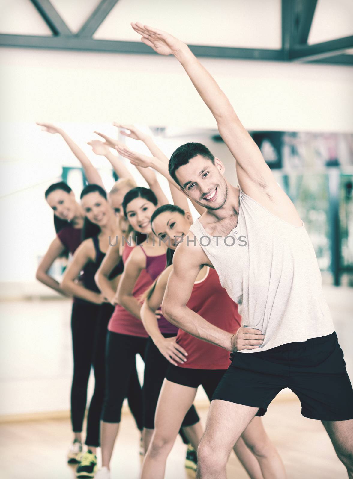 group of smiling people stretching in the gym by dolgachov