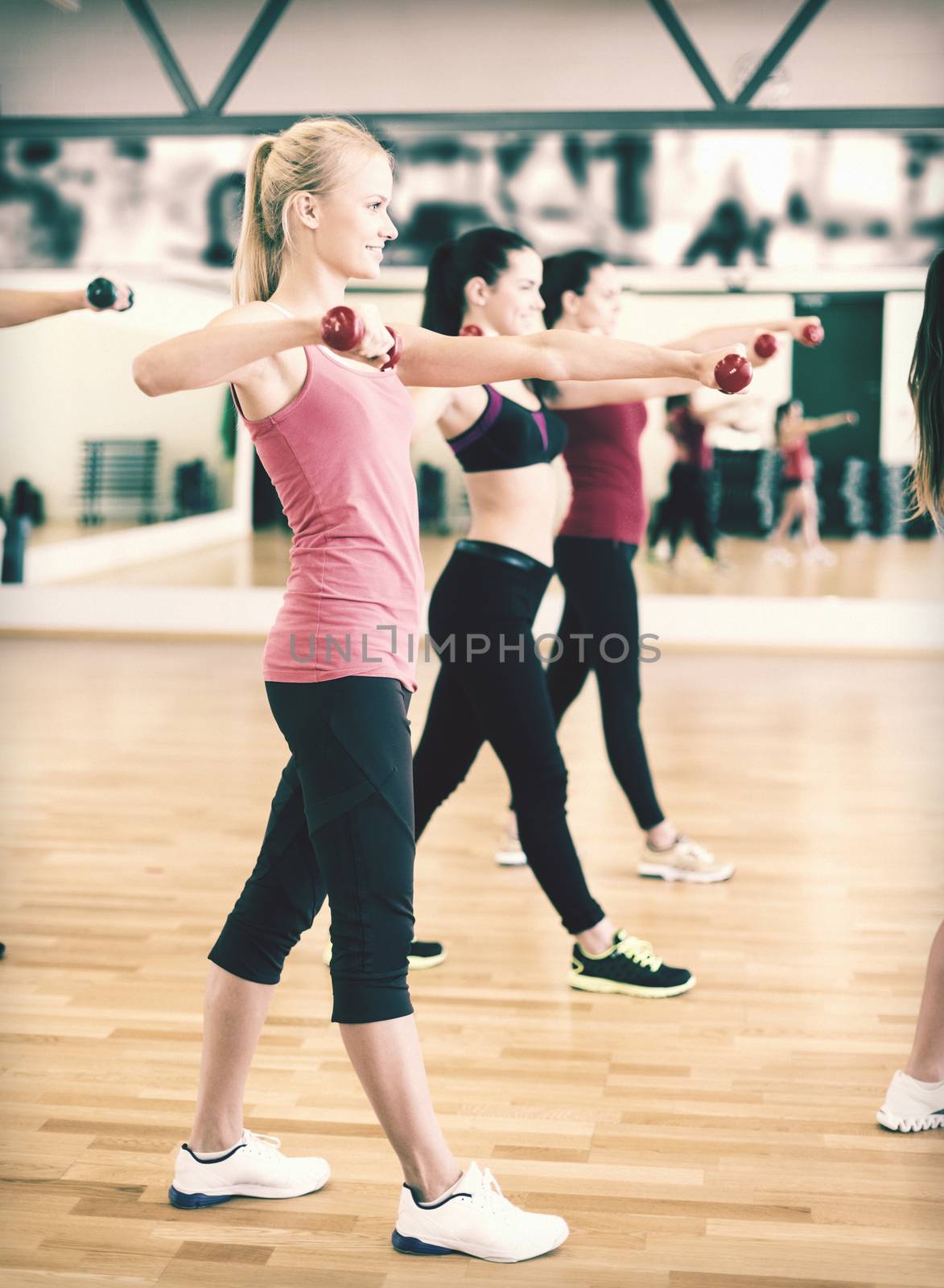 group of smiling people working out with dumbbells by dolgachov