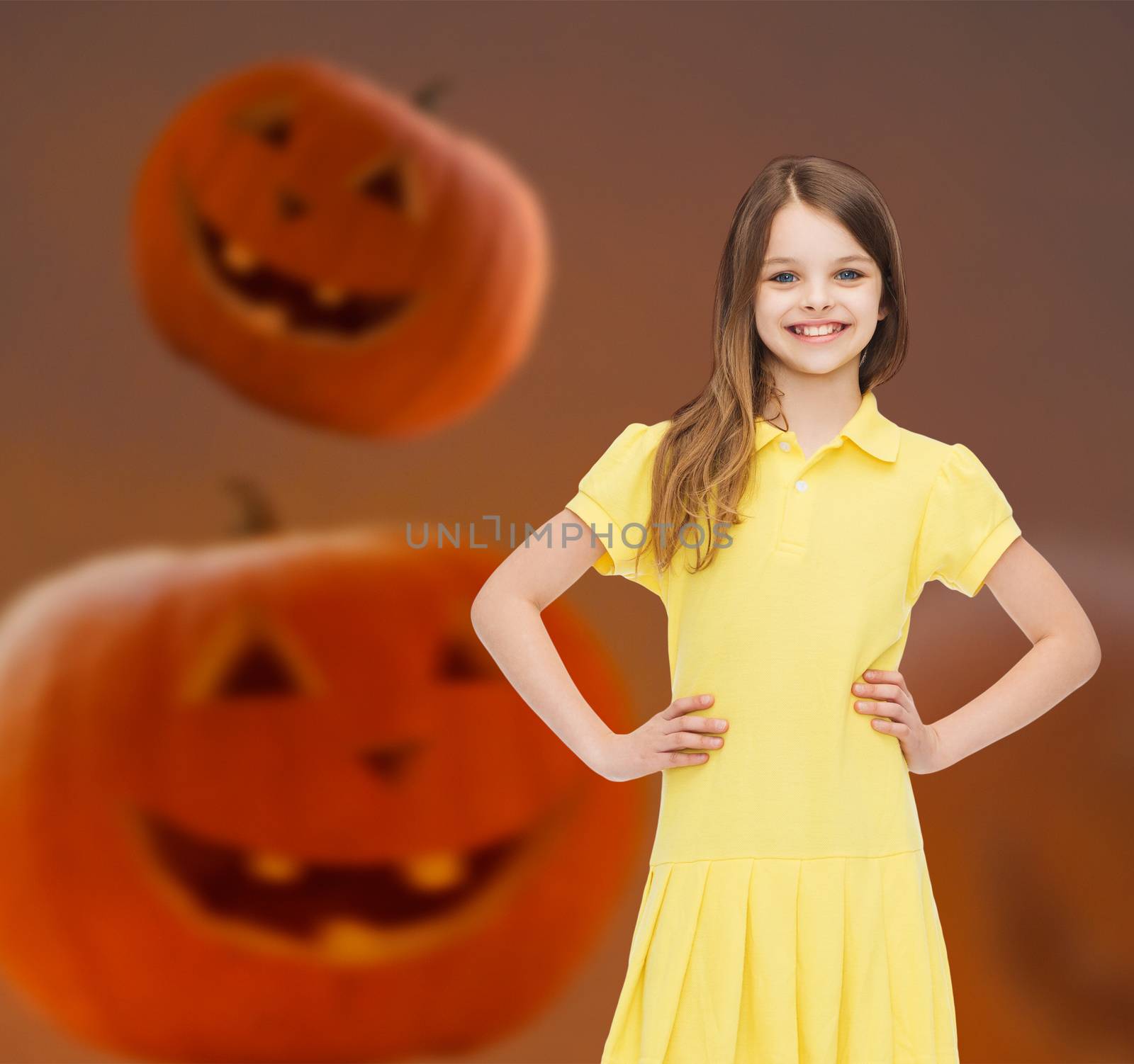 holidays, childhood, happiness and people concept - smiling little girl in dress over halloween pumpkins background