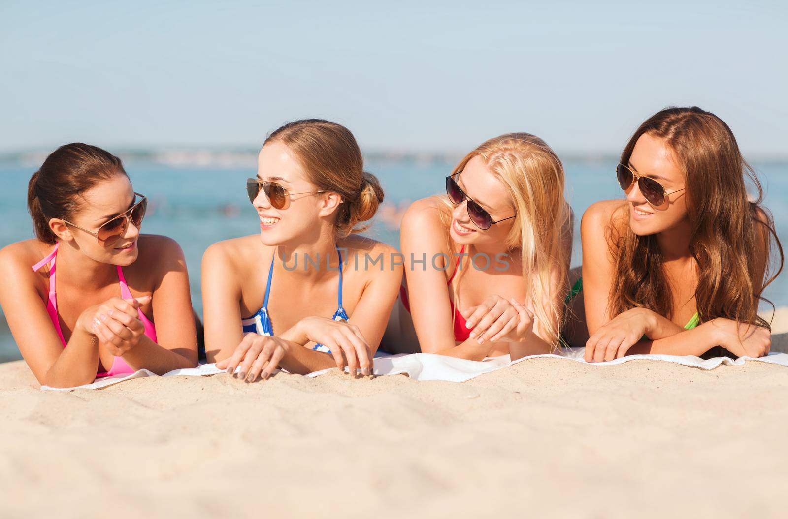 summer vacation, holidays, travel and people concept - group of smiling young women in sunglasses lying on beach