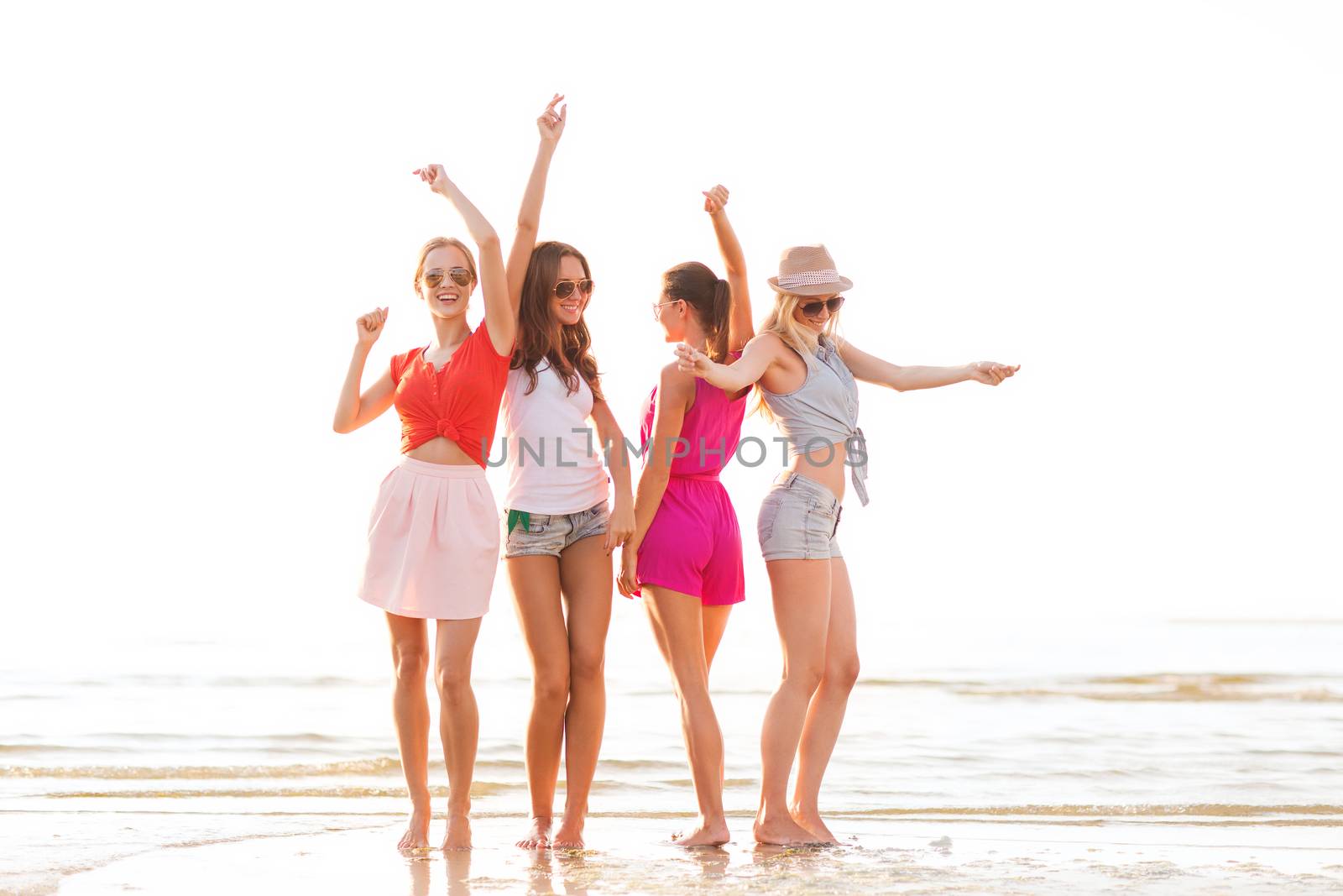 summer vacation, holidays, travel and people concept - group of smiling young women in sunglasses and casual clothes dancing on beach