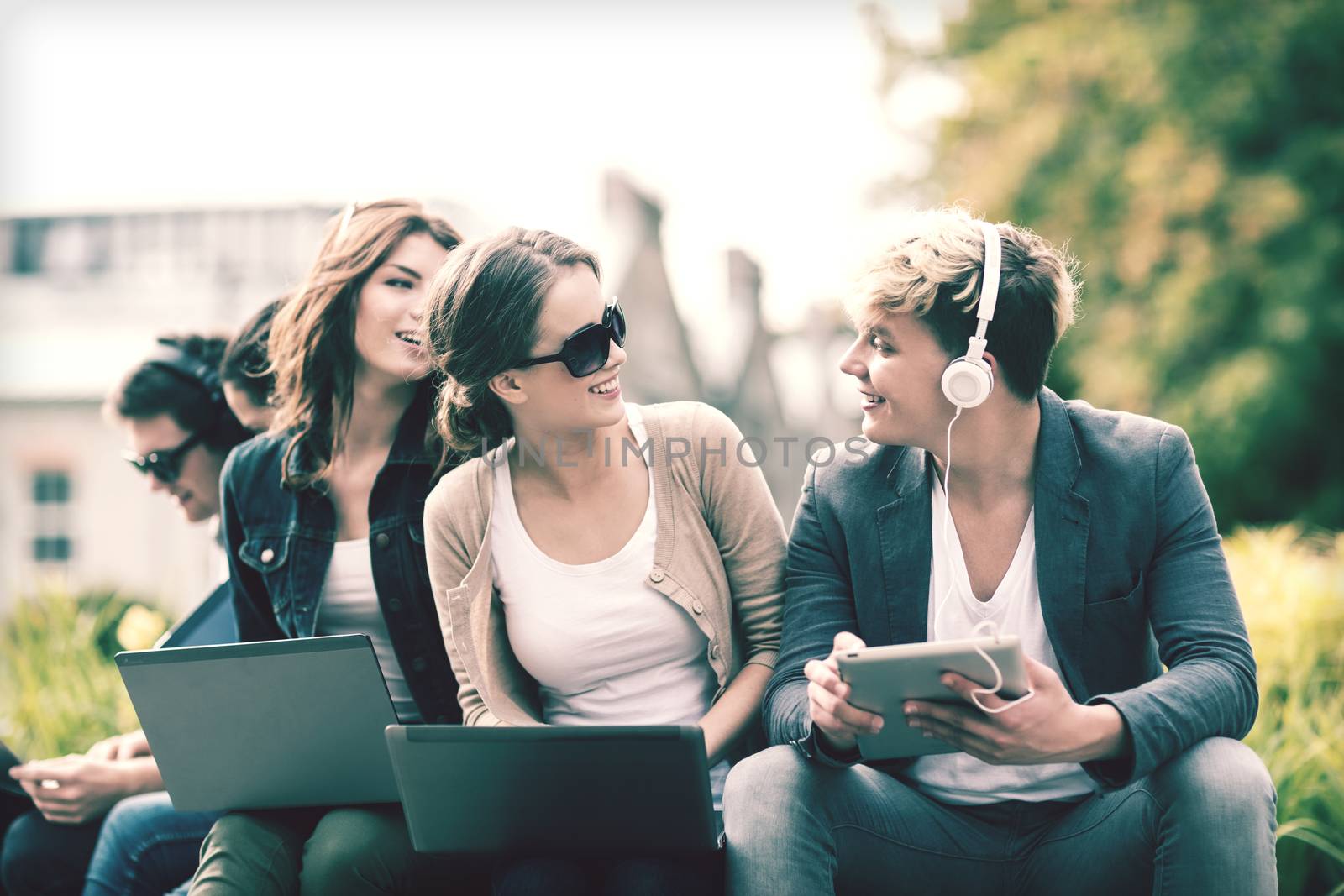 summer, internet, education, campus and teenage concept - group of students or teenagers with laptop and tablet computers hanging out