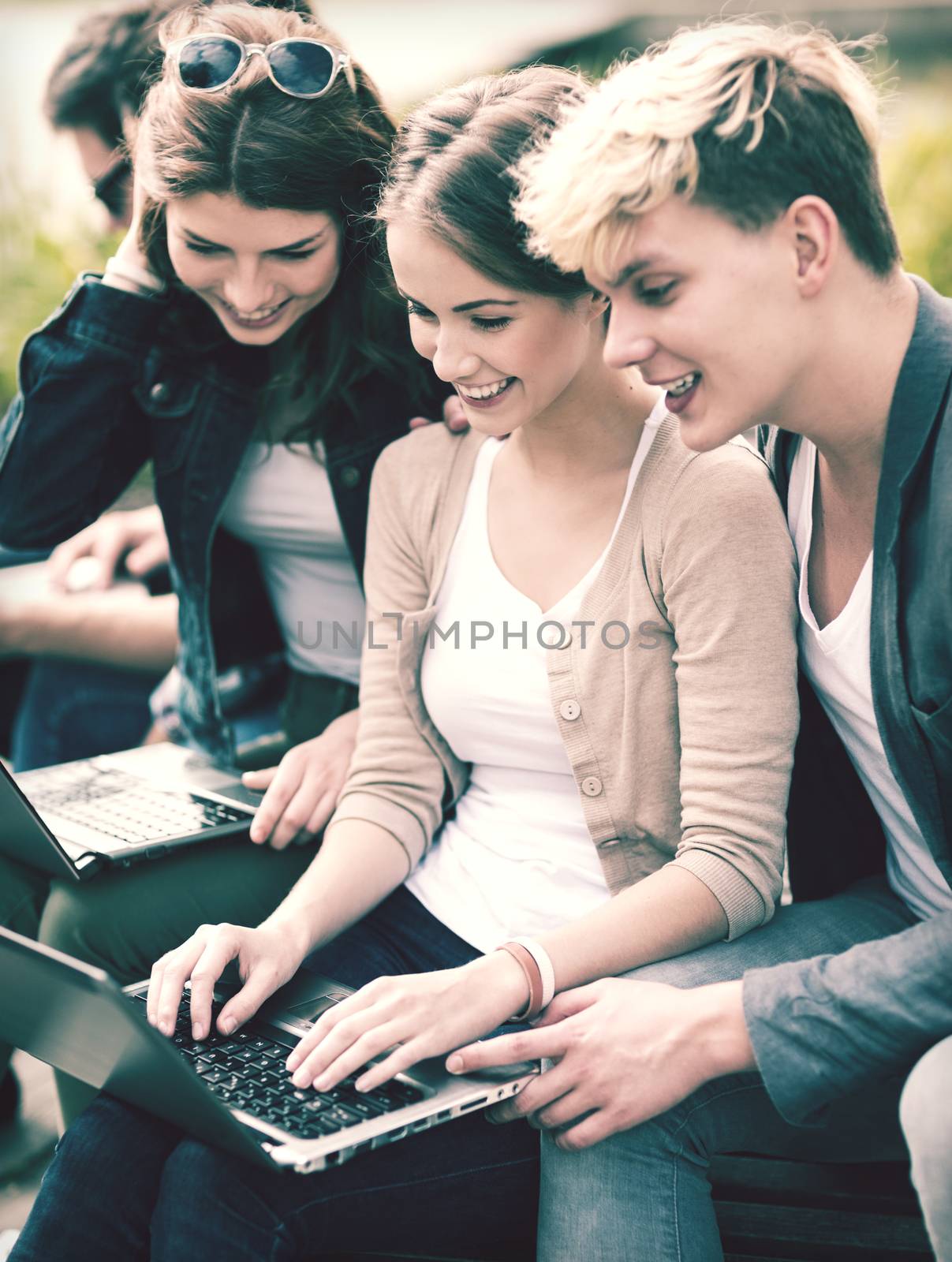 summer, internet, education, campus and teenage concept - group of students or teenagers with laptop computers hanging out