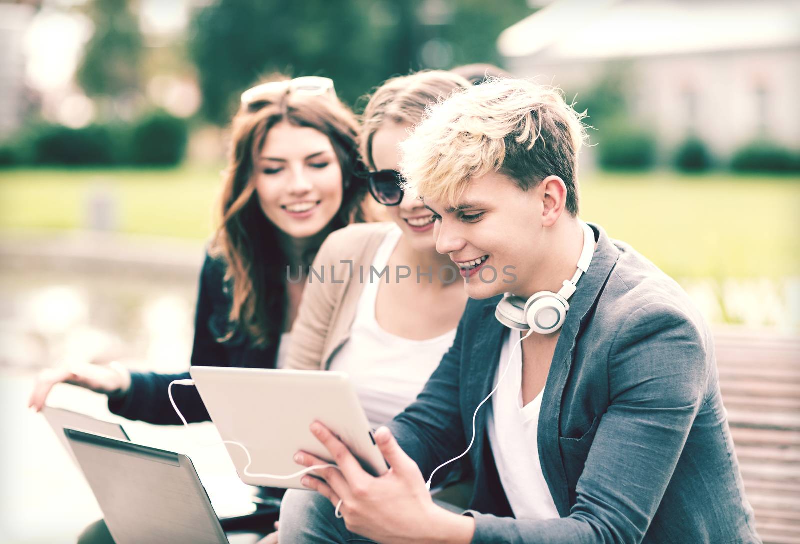 summer, internet, education, campus and teenage concept - group of students or teenagers with laptop and tablet computers hanging out