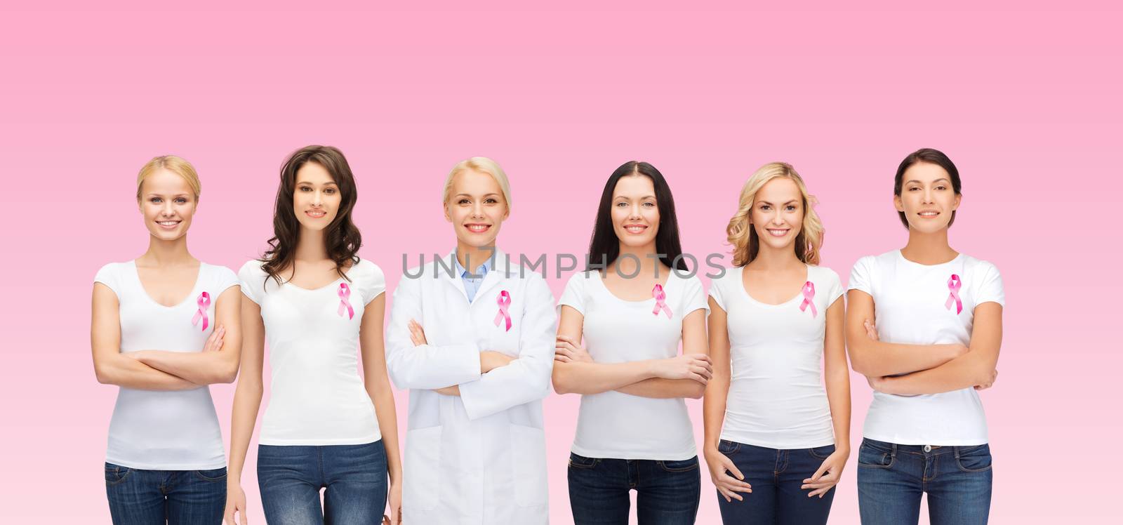 healthcare, people and medicine concept - group of smiling women in blank t-shirts with breast cancer awareness ribbons over pink background