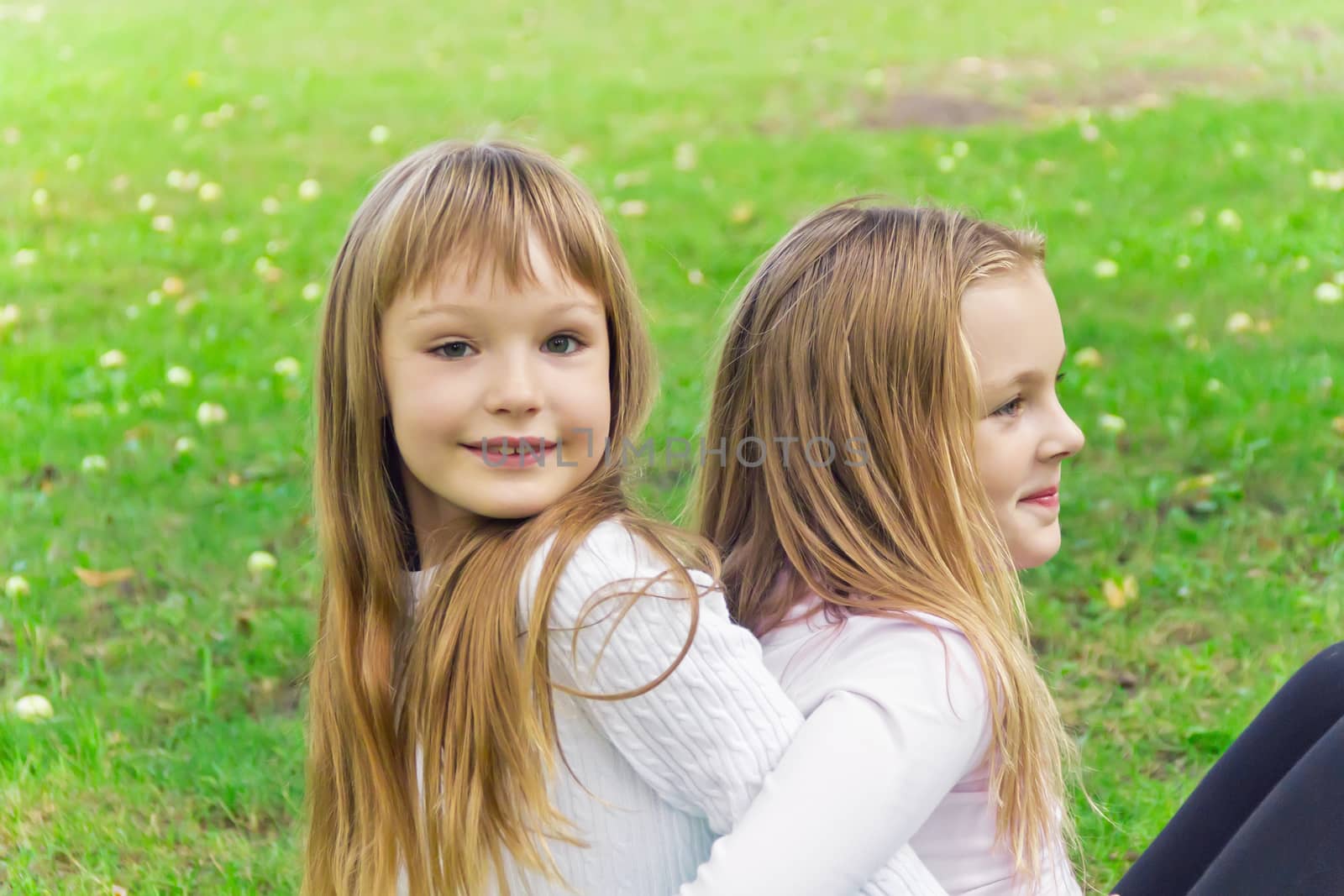 Photo of two girls sitting on grass in summer