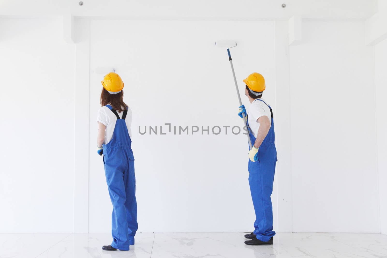 two workmen painting white wall