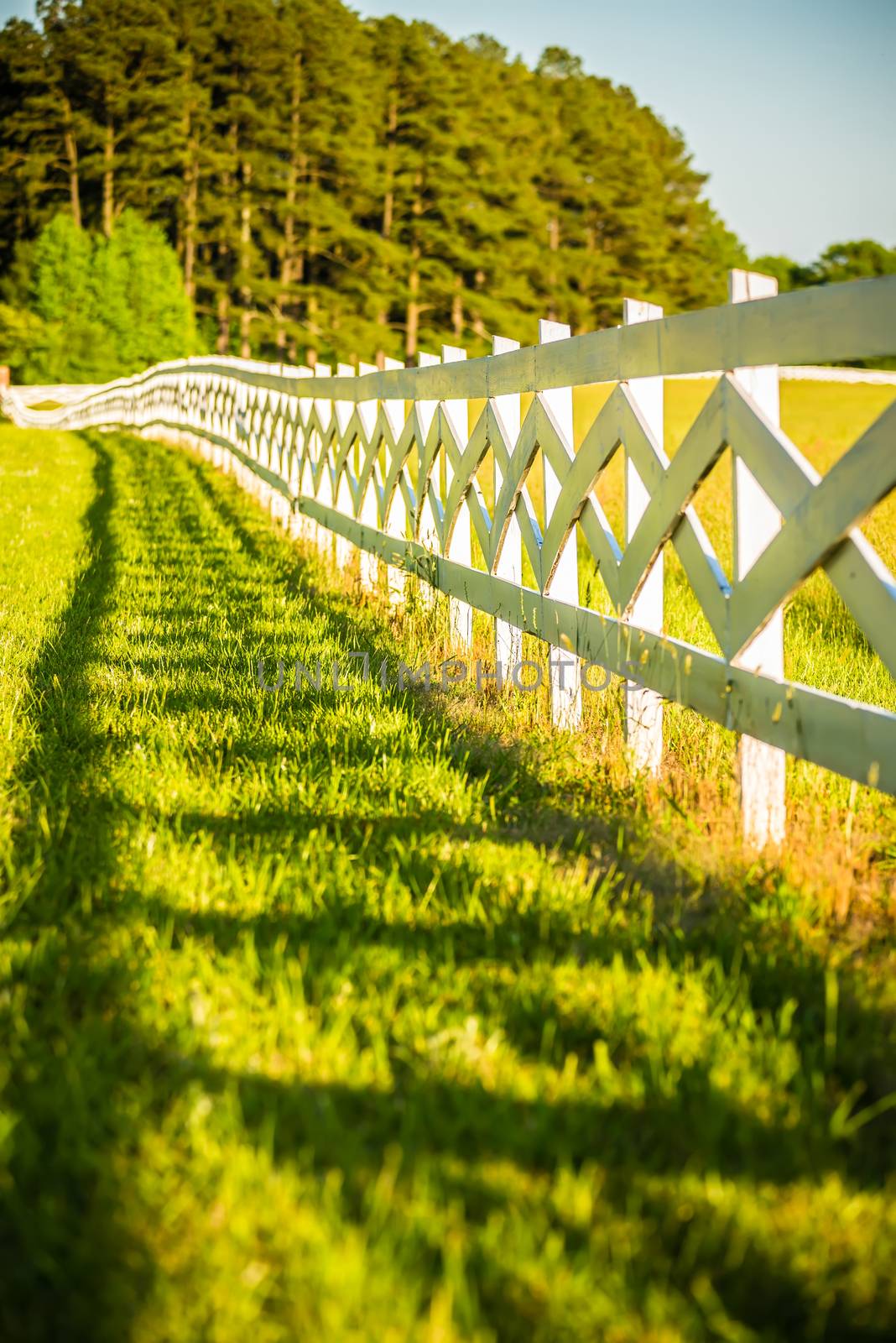  white fence leading up to a big red barn