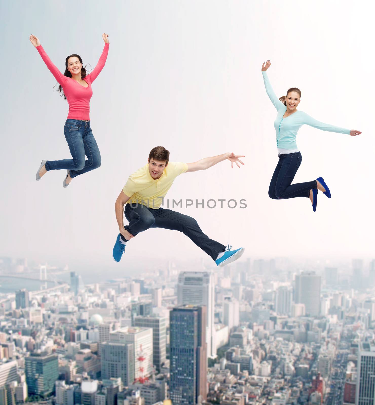 happiness, freedom, friendship, movement and people concept - group of smiling teenagers jumping in air over city background