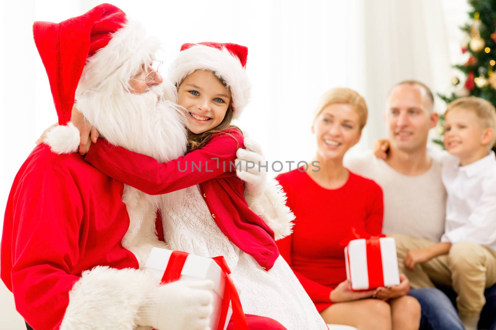 smiling family with santa claus and gifts at home by dolgachov