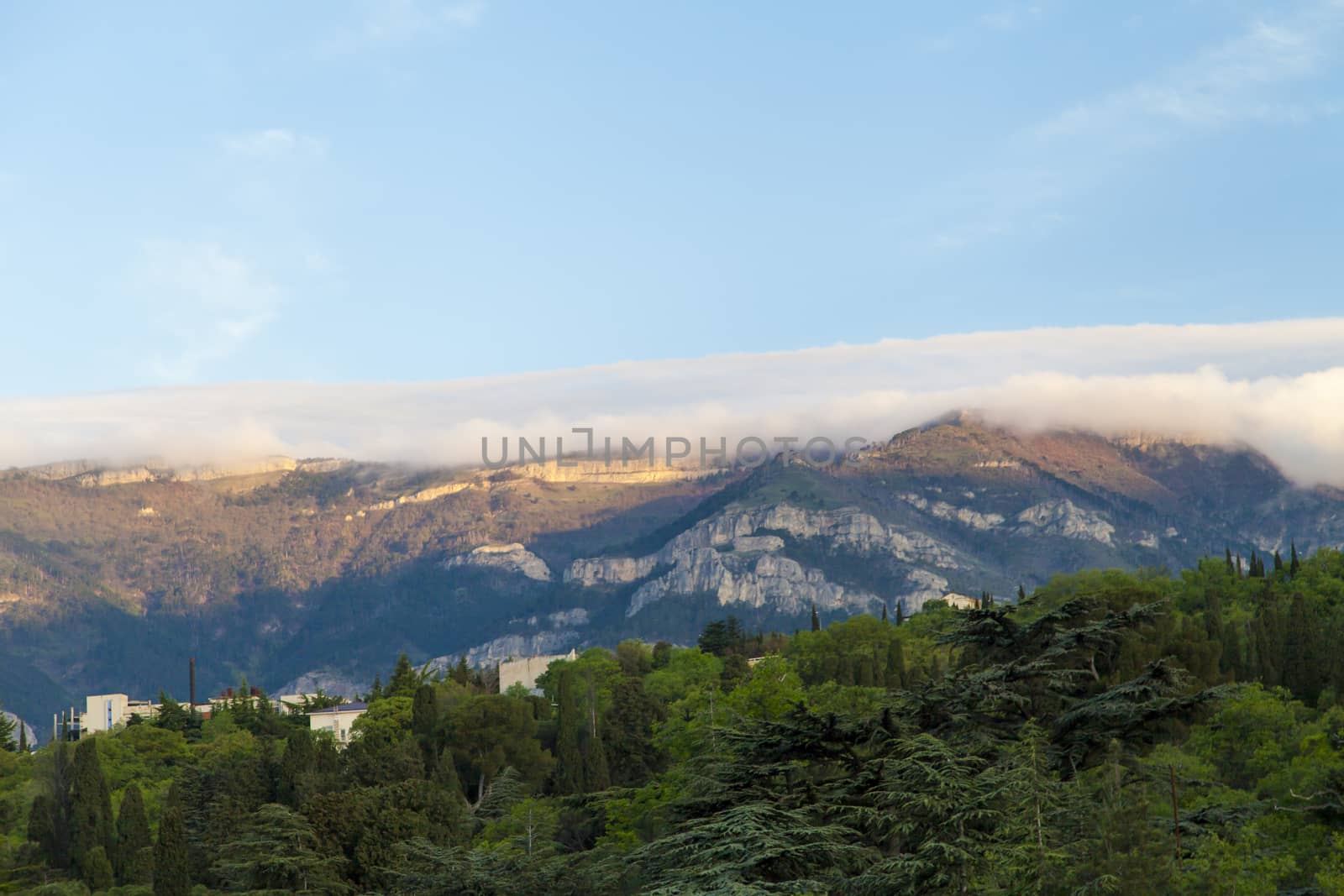 Mountains by the sea at sunrise in beams of the soft sun