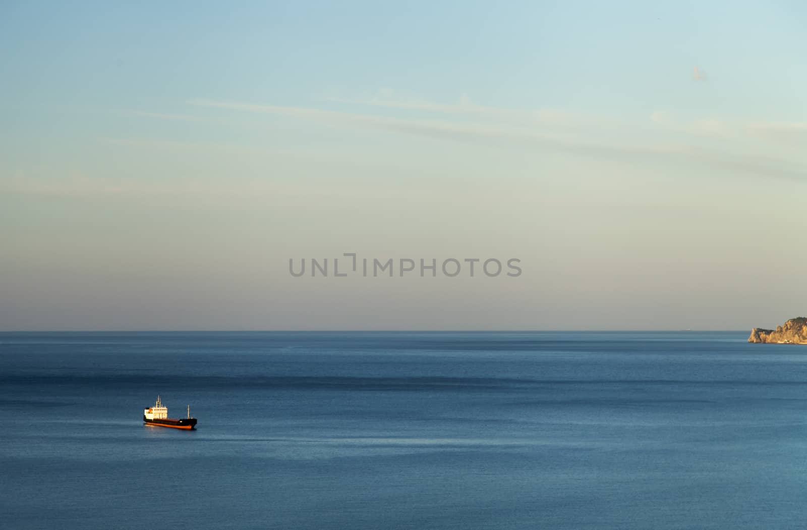 Mountains by the sea at sunrise in beams of the soft sun