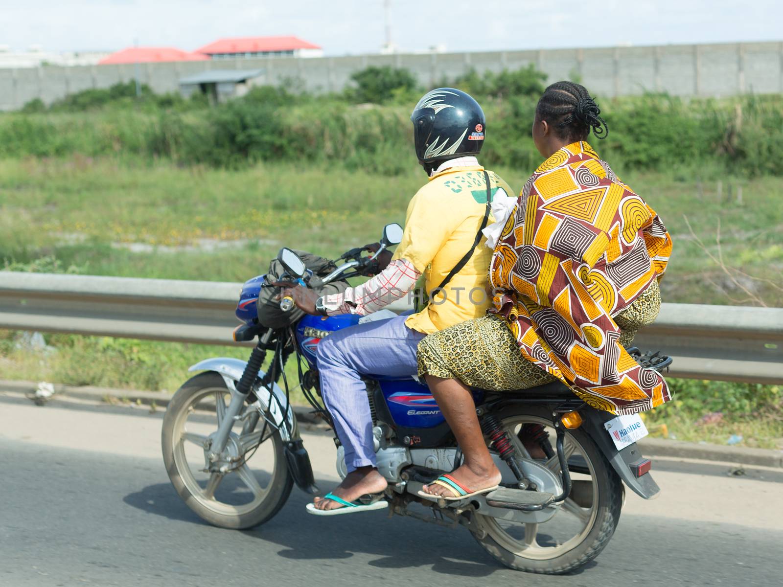 Cotonou, Benin: May 26: A woman rides a hired Motorcycle taxi, the most common means of hired transportation in the city, on May 26, 2015 in Cotonou, Benin.