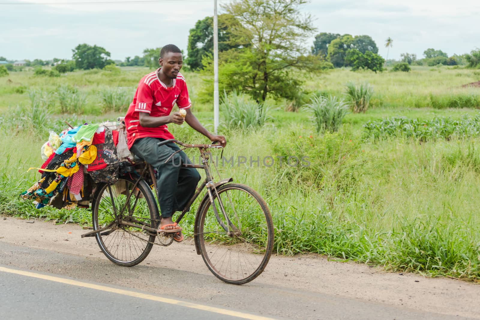 Street vendor riding his back full of merchandise  by derejeb