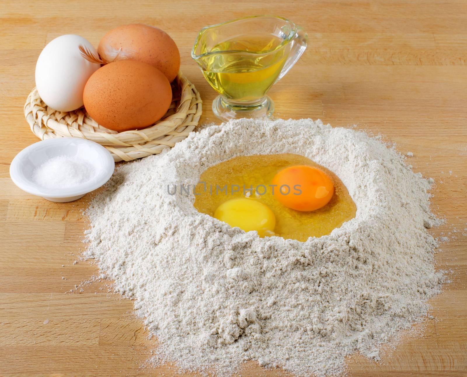 Preparing Dough with Raw Ingredients. Flour, Eggs, Salt and Olive Oil closeup on Wooden Cutting Board