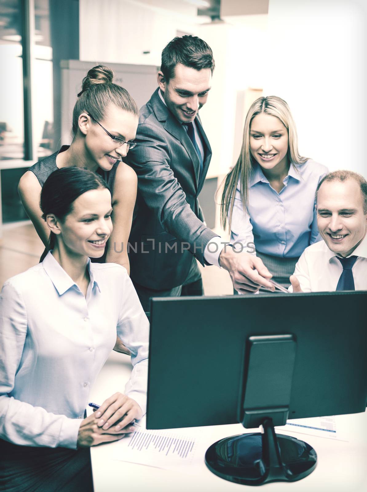 business, technology and office concept - smiling business team with computer monitor having discussion in office