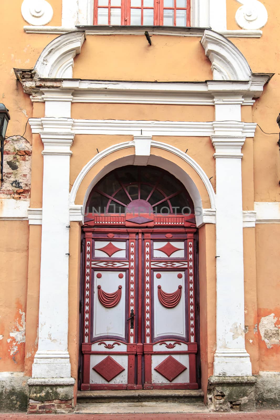 Close up front view of old historical wooden door of yellow and orange building.