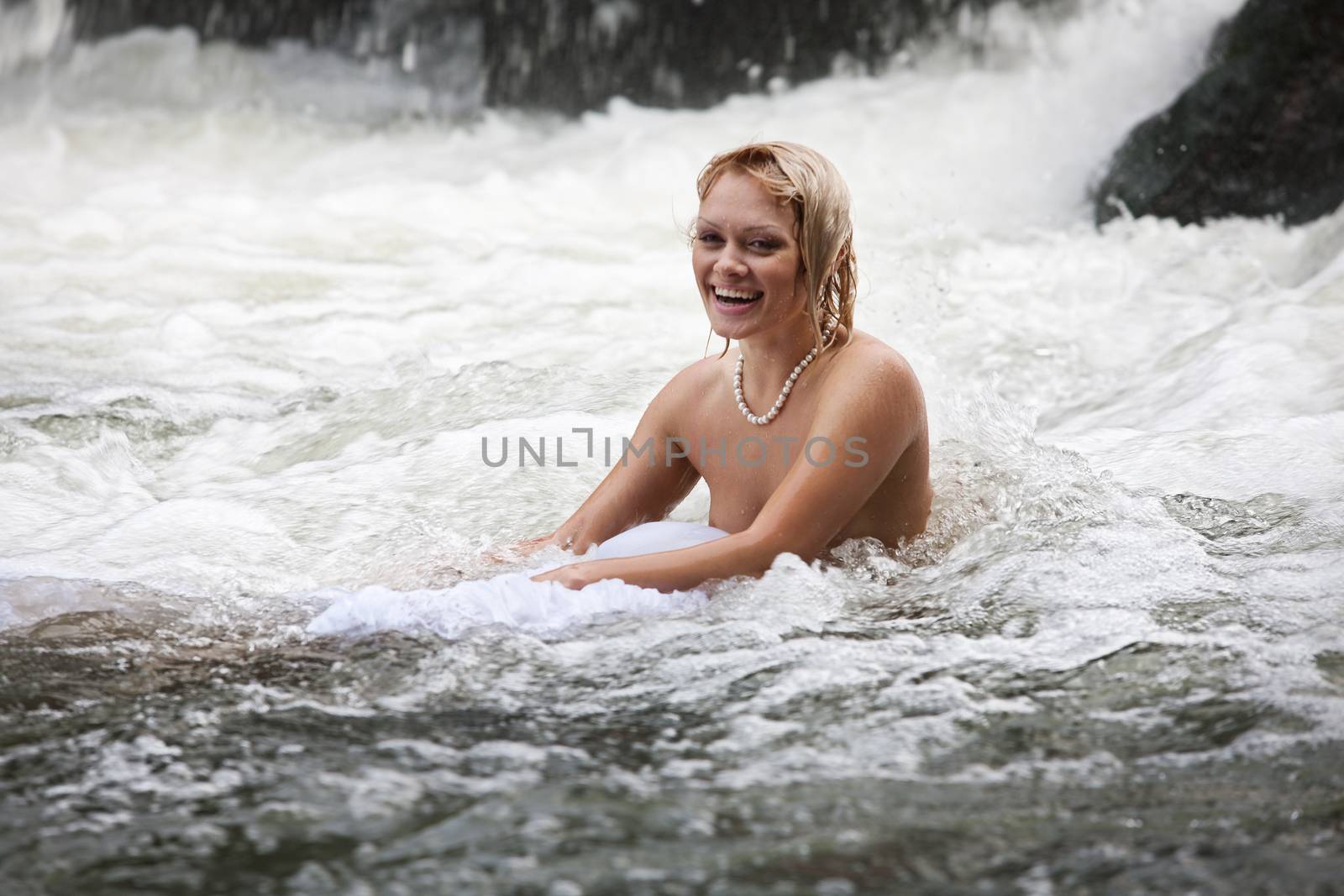 Young naked woman swimming in a river