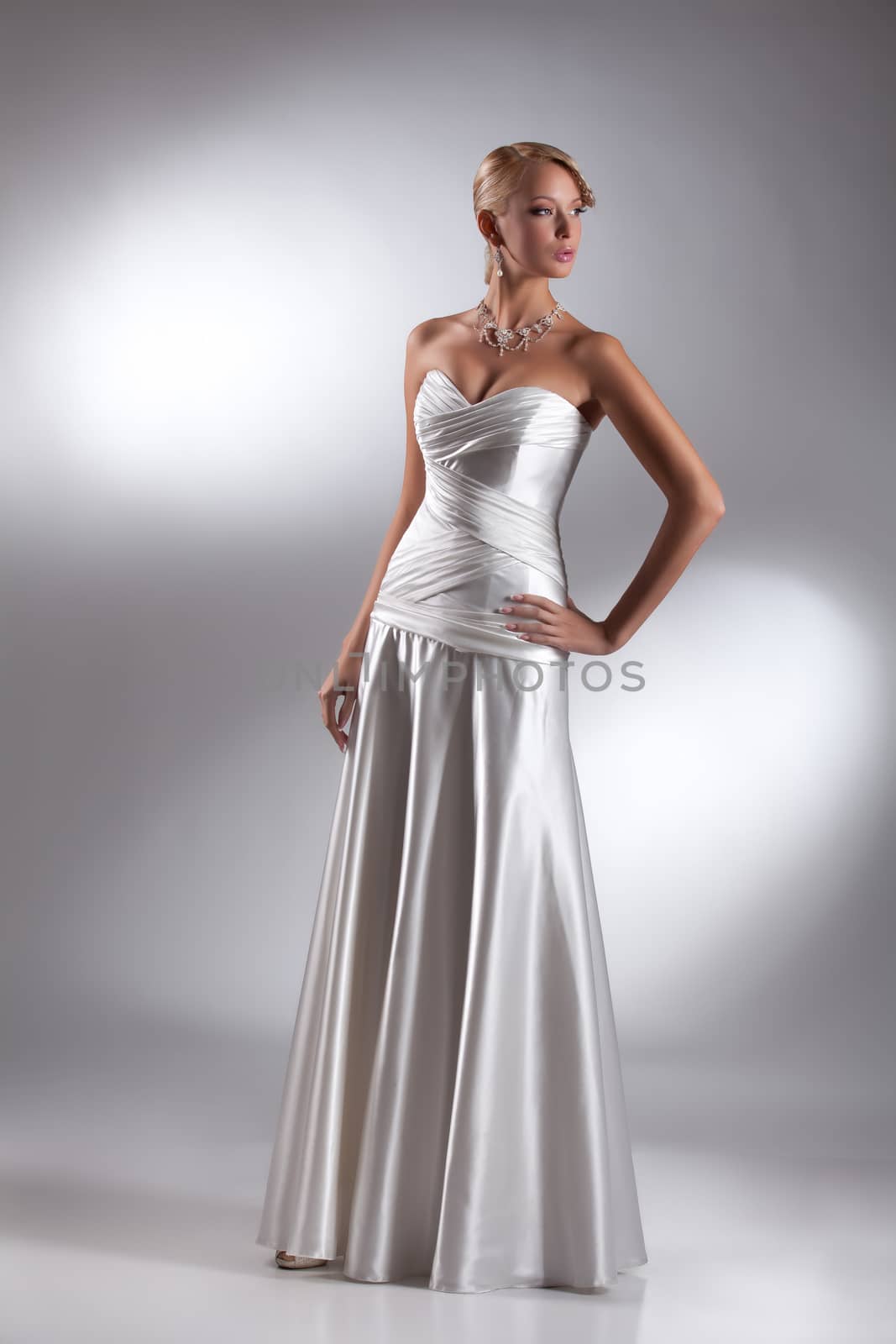 Young beautiful blonde woman in a wedding dress on a studio background