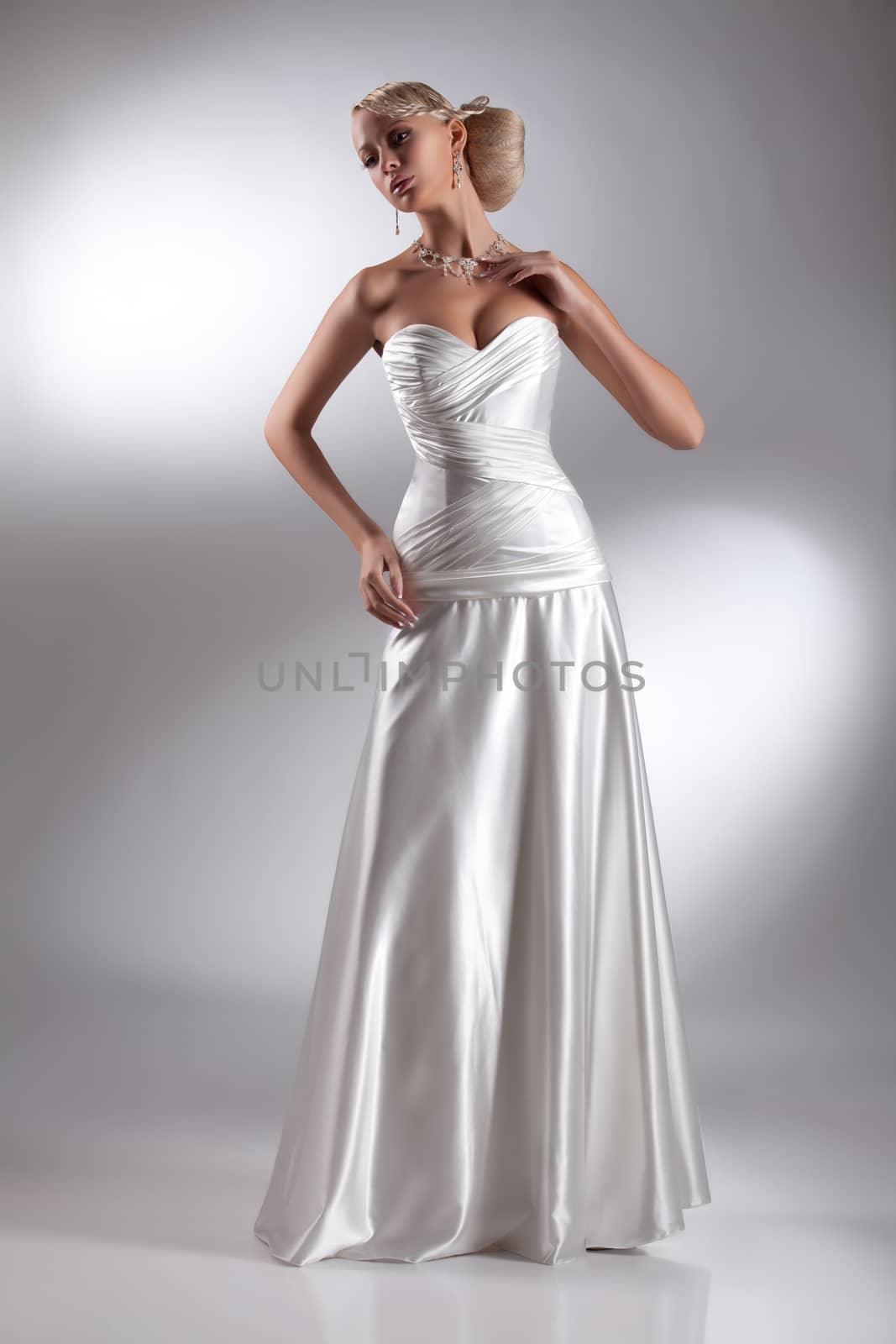 Young beautiful blonde woman in a wedding dress on a studio background