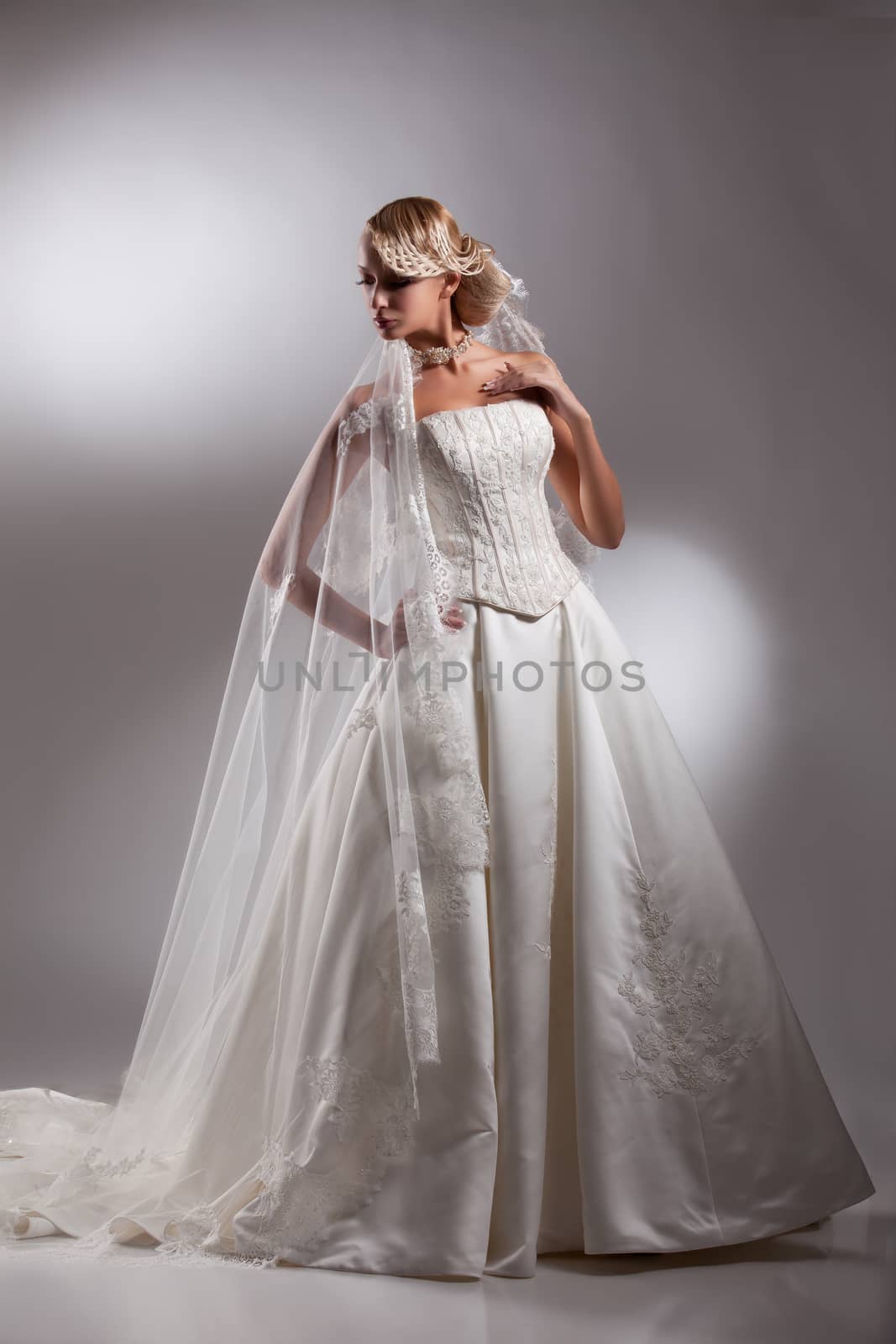 Young beautiful blonde woman in a wedding dress on a studio background