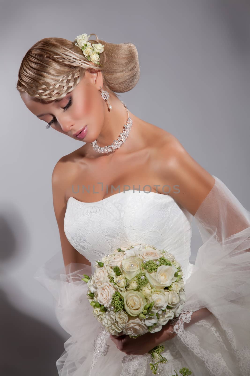 Young beautiful blonde woman in a wedding dress on a studio background