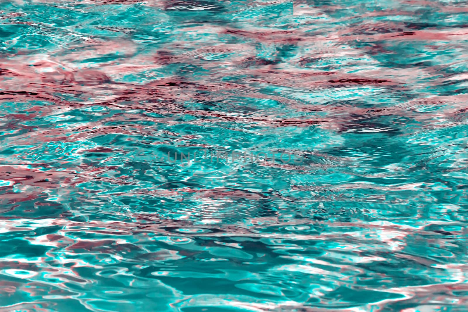The surface of the water in the pool, sparkling with beautiful colored glare due to reflection of light. A background image.