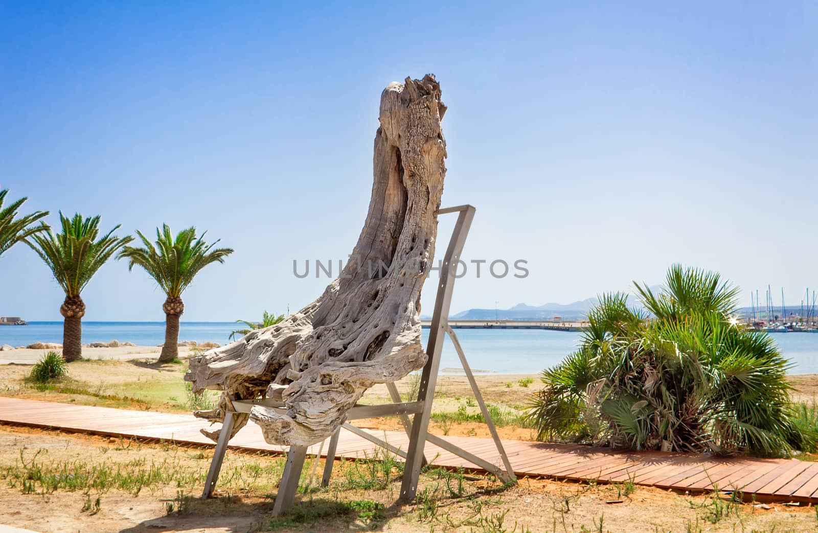 On the beach near the pedestrian walkway is a decorative feature out of the trunk of an old tree on a metal stand.