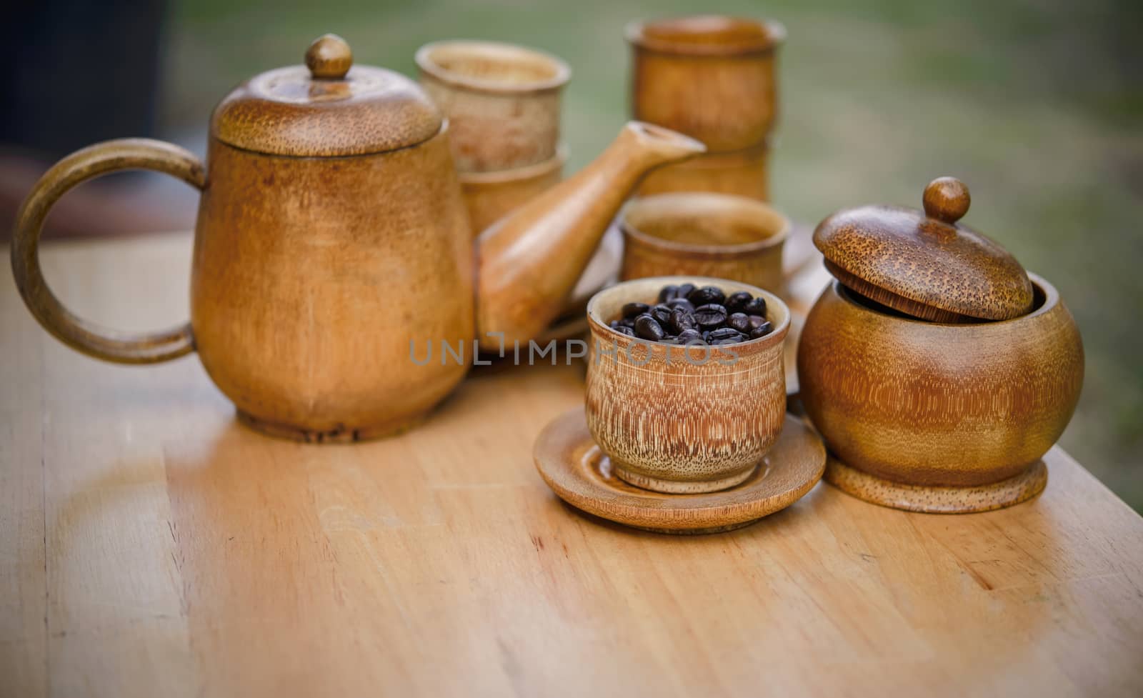 Coffee beans, cup of coffee and teapot on wooden desk. Set of cafe