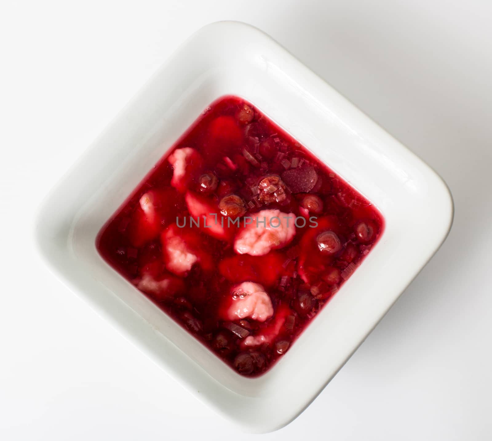 Strawberry, raspberry and rhubarb soup with dumplings isolated on white.