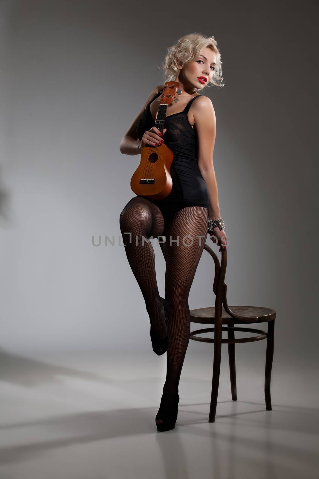 Young beautiful blonde woman with a small hawaiian guitar